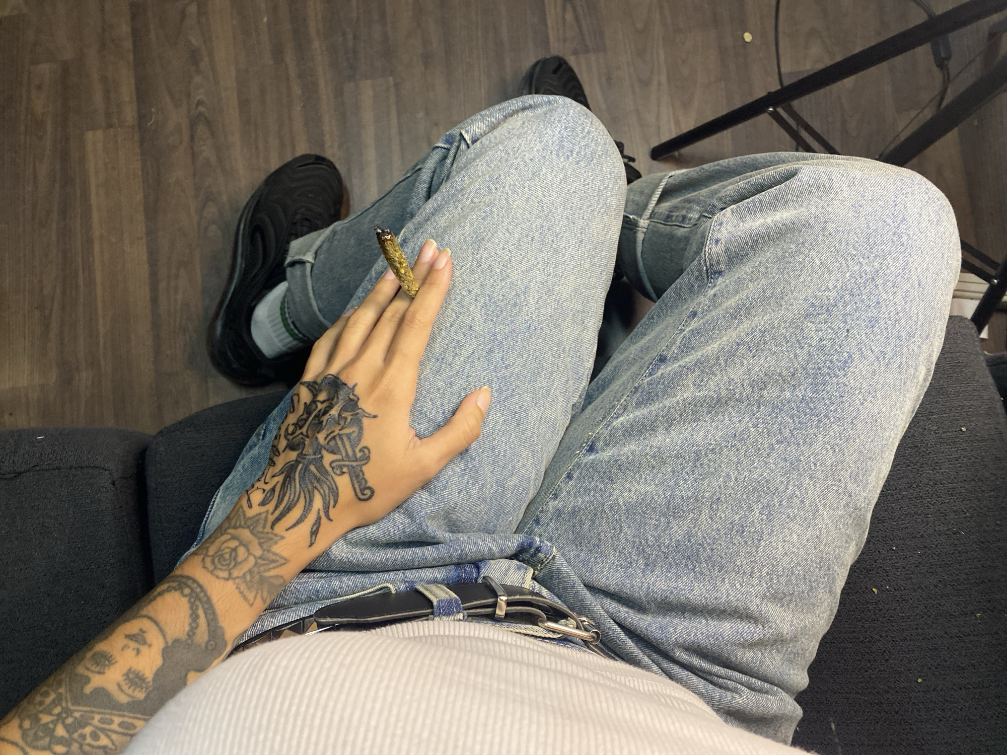 Person with tattoos sits on gray sofa in Llavallol