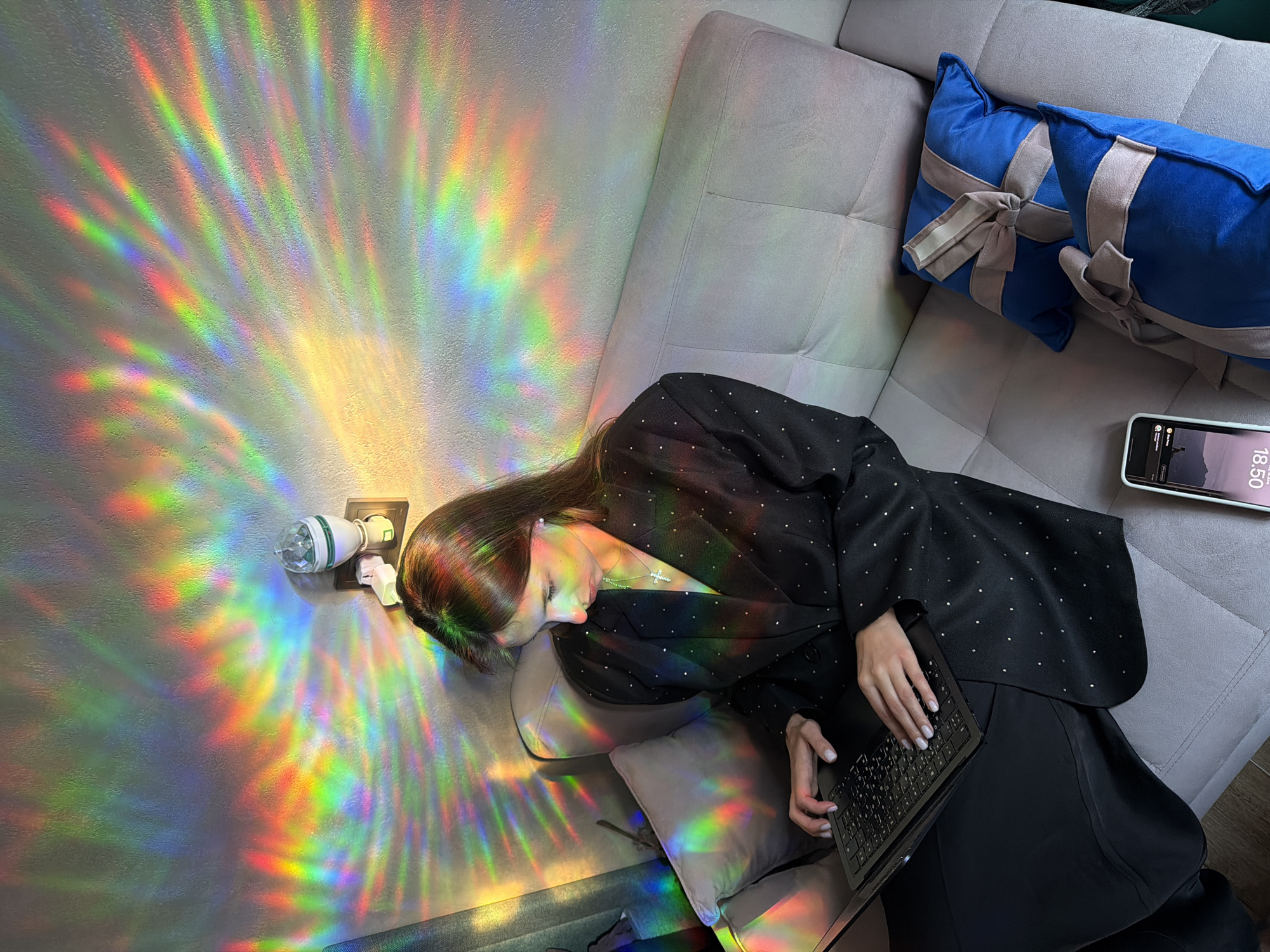 Relaxed evening on a couch, rainbow projector lighting the room