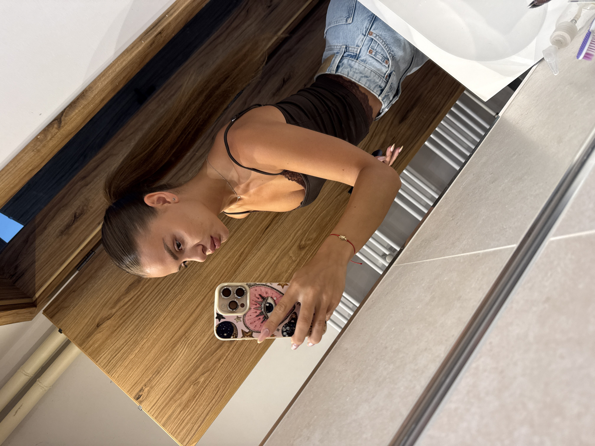 Mirror selfie in a modern bathroom, dark top and denim