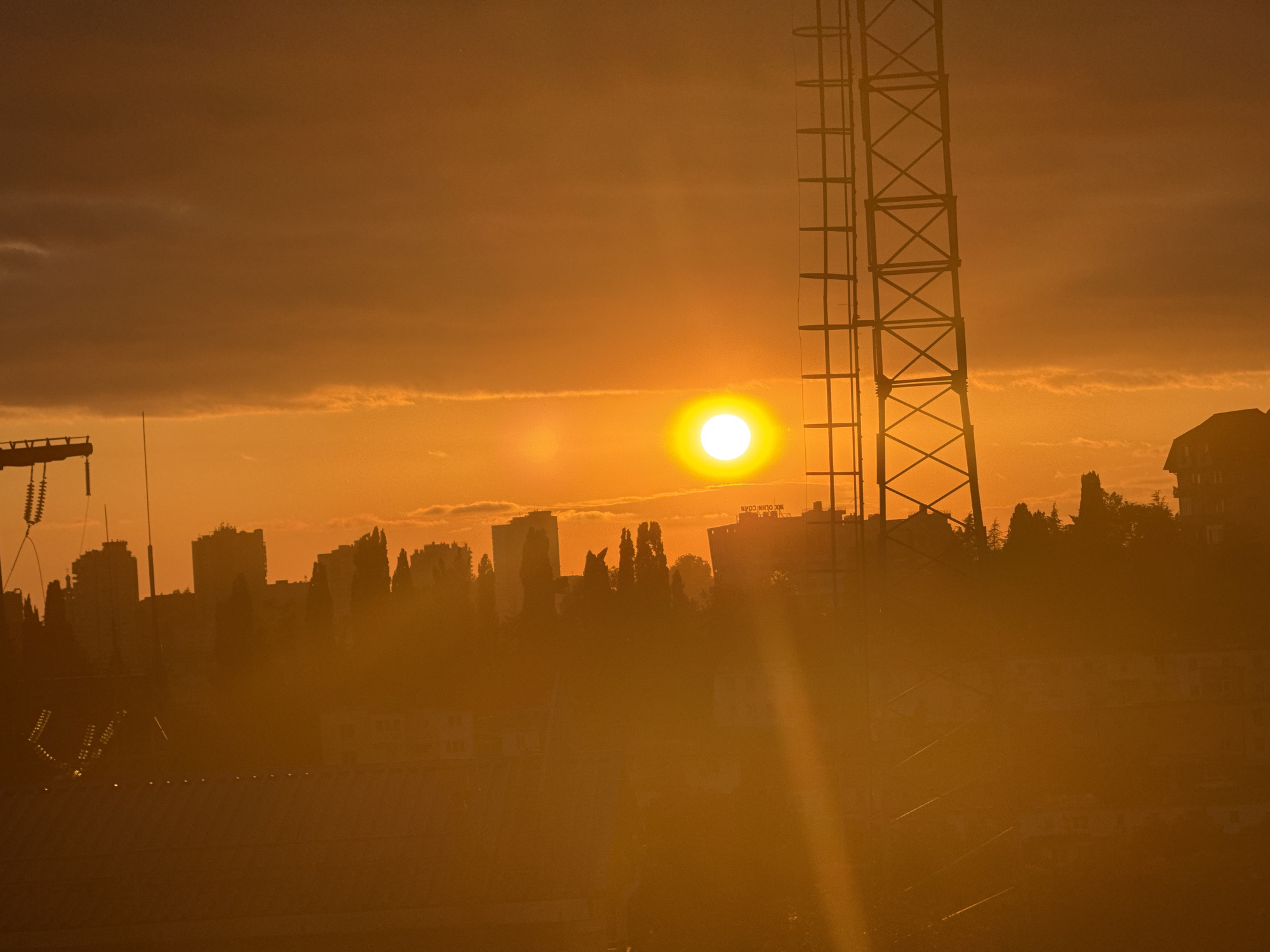 Orange sunset silhouettes Sochi's skyline at dusk
