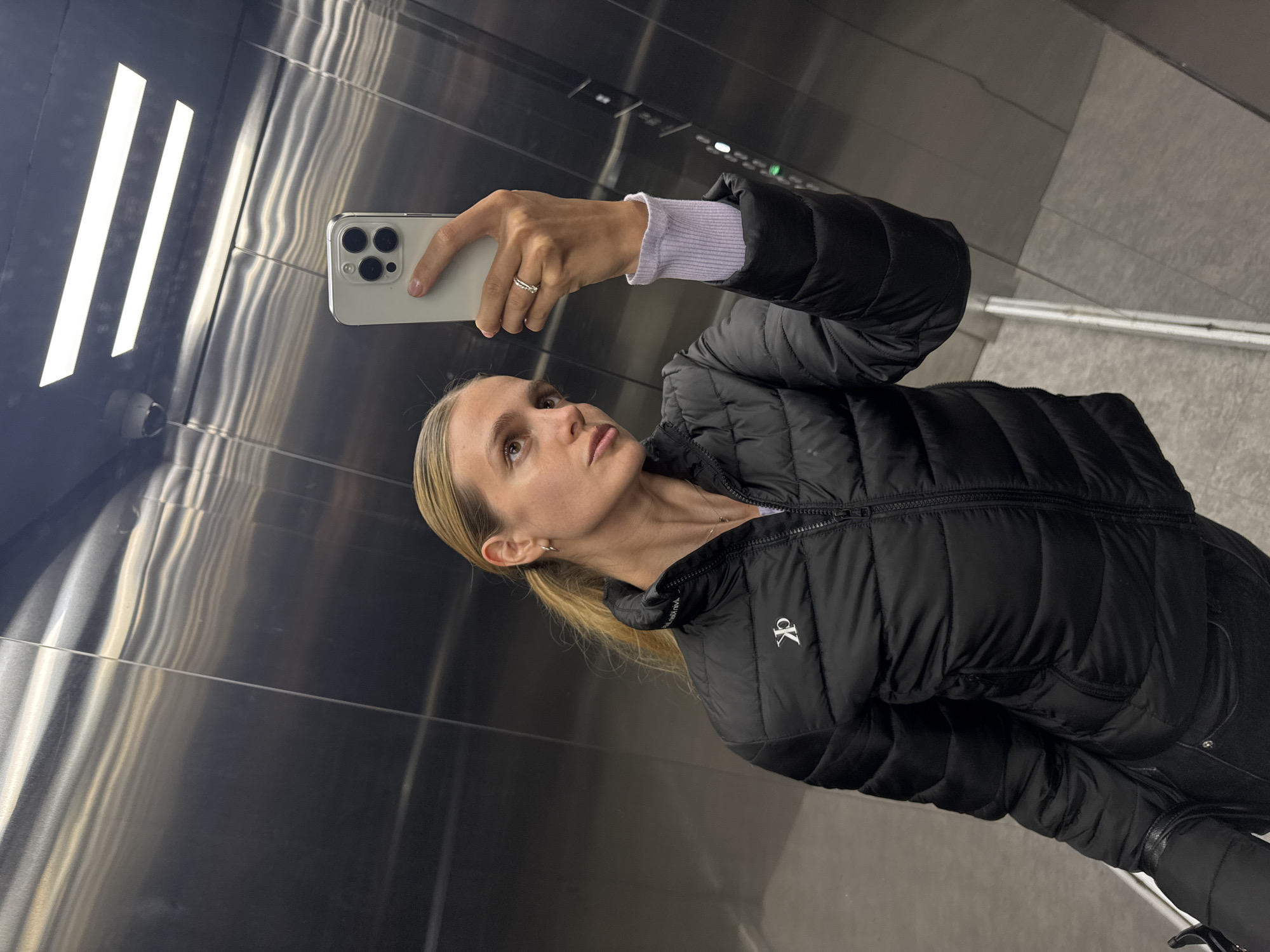 Woman Takes Elevator Selfie with iPhone in CK Jacket