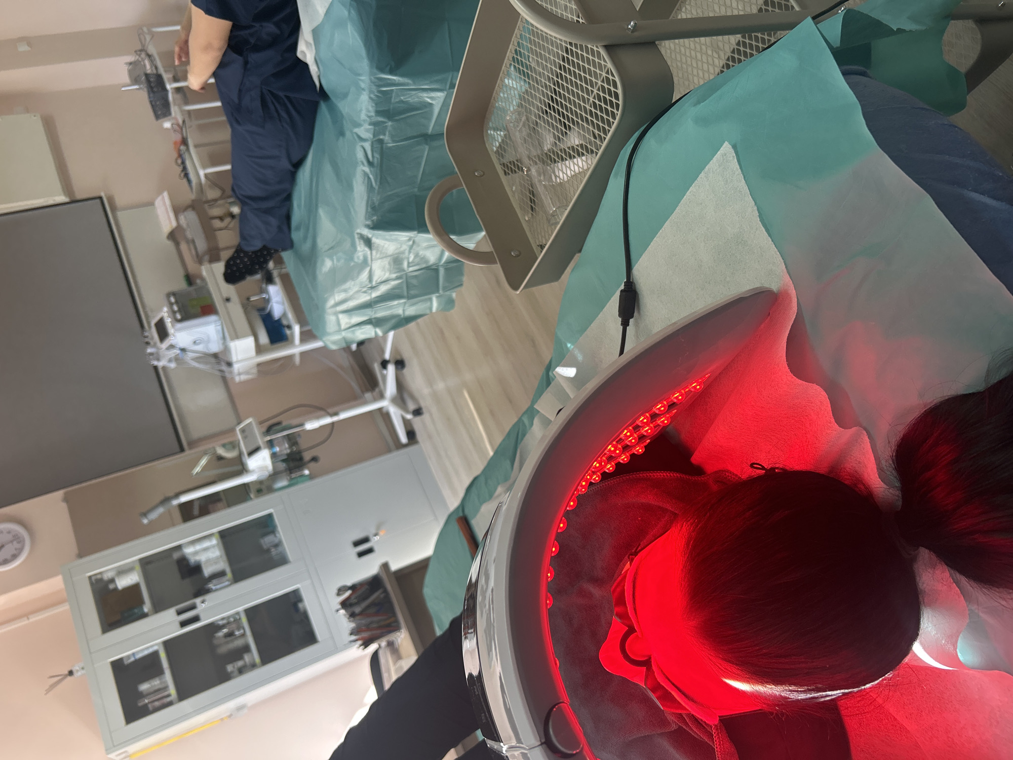 Person receives red light therapy treatment under dome device