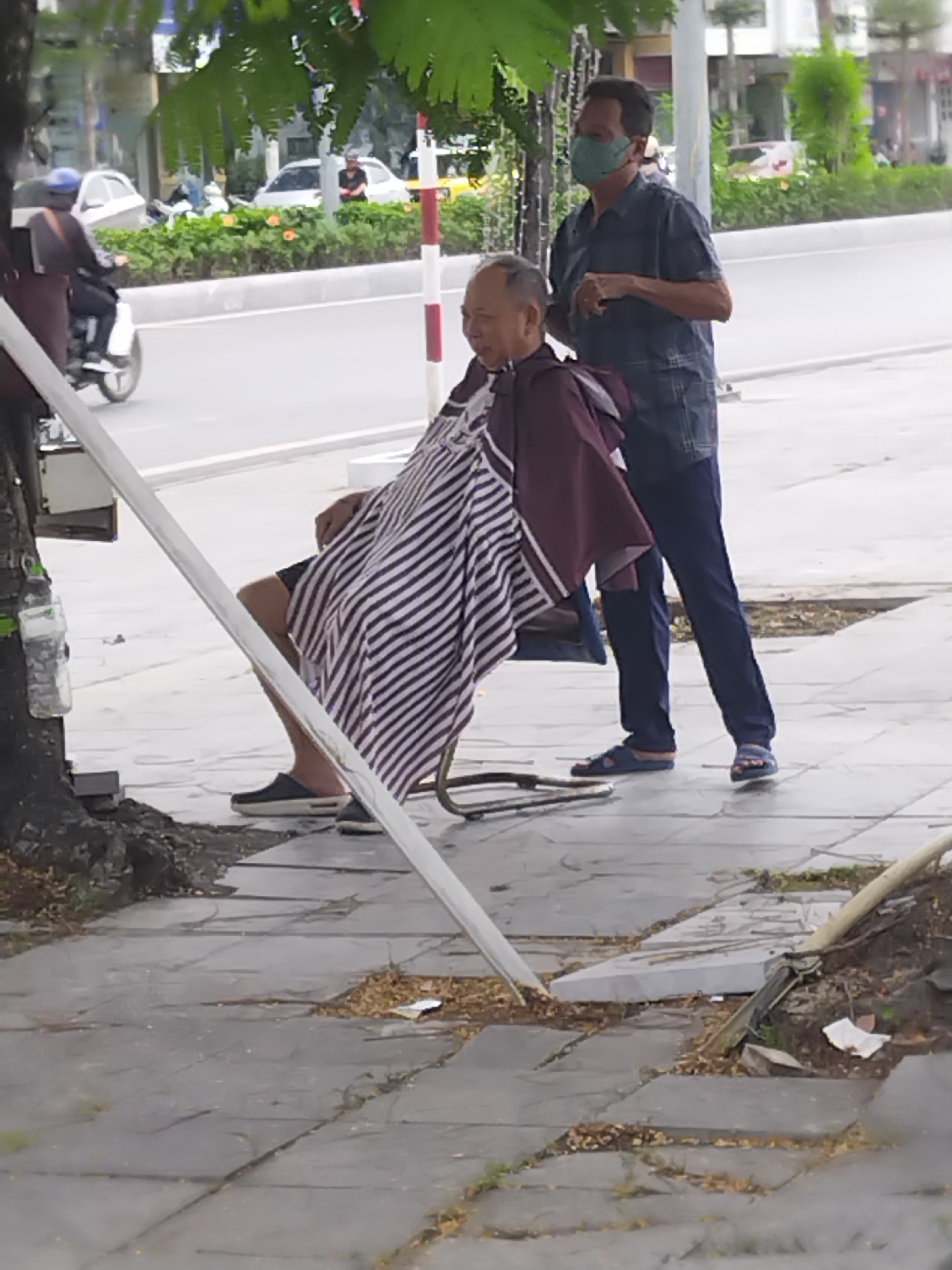 Street barber provides outdoor haircut service in Hong Gai Ward