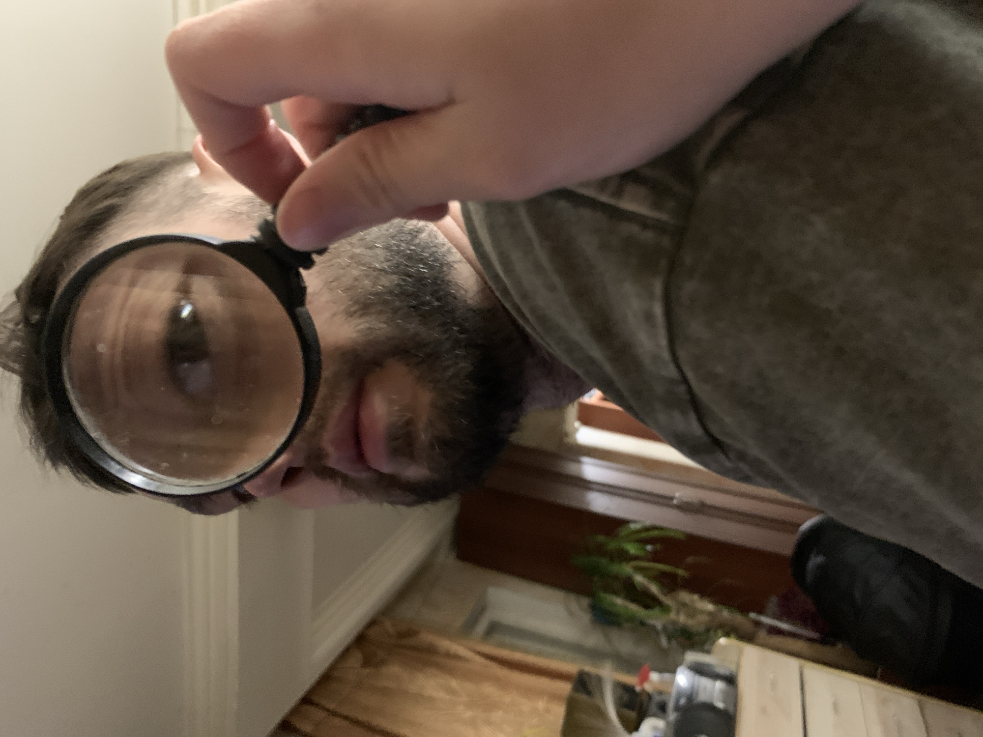 Man uses magnifying glass and mirror indoors in Zasechnyi