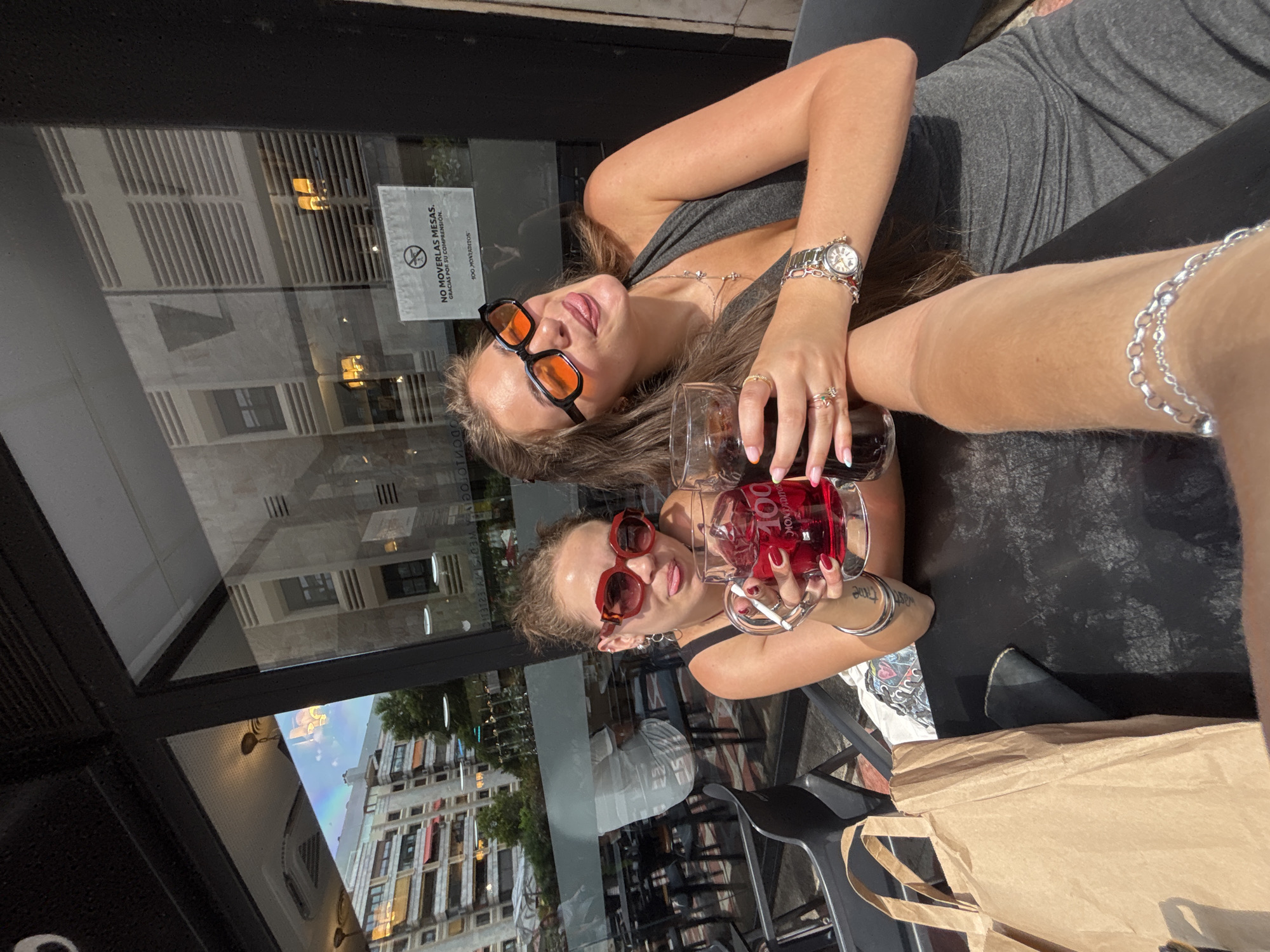Women pose at outdoor Madrid bar table