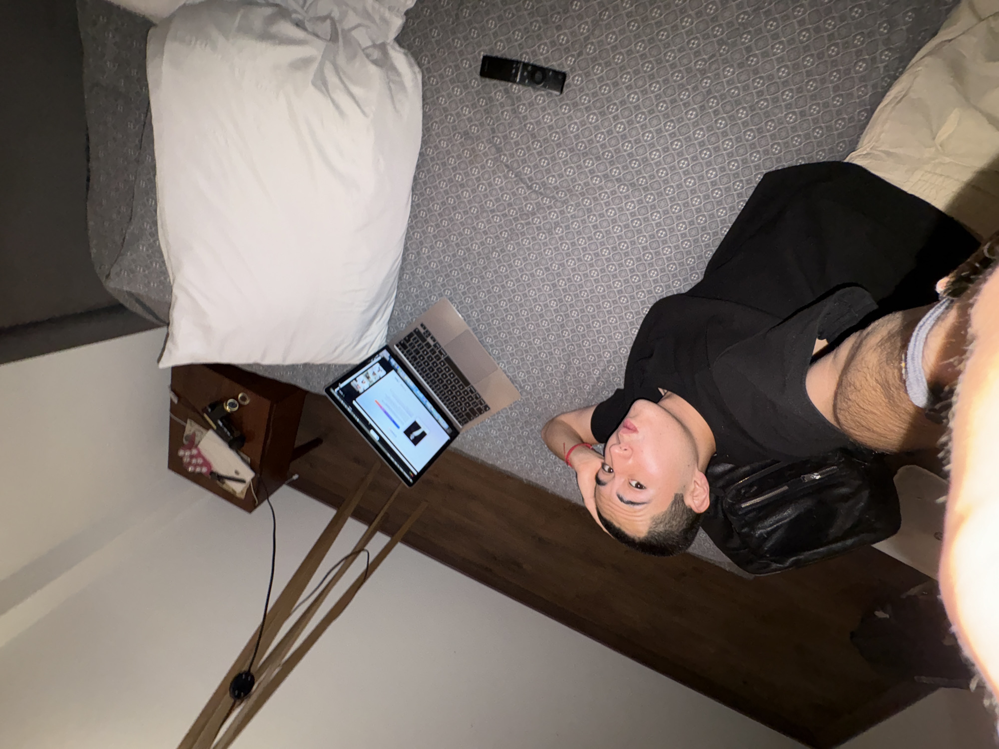 Person rests with laptop in bedroom, Mexico