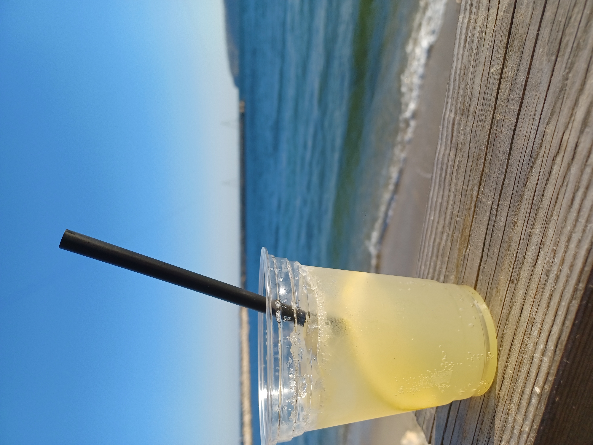 Beverage in plastic cup spotted on wooden surface