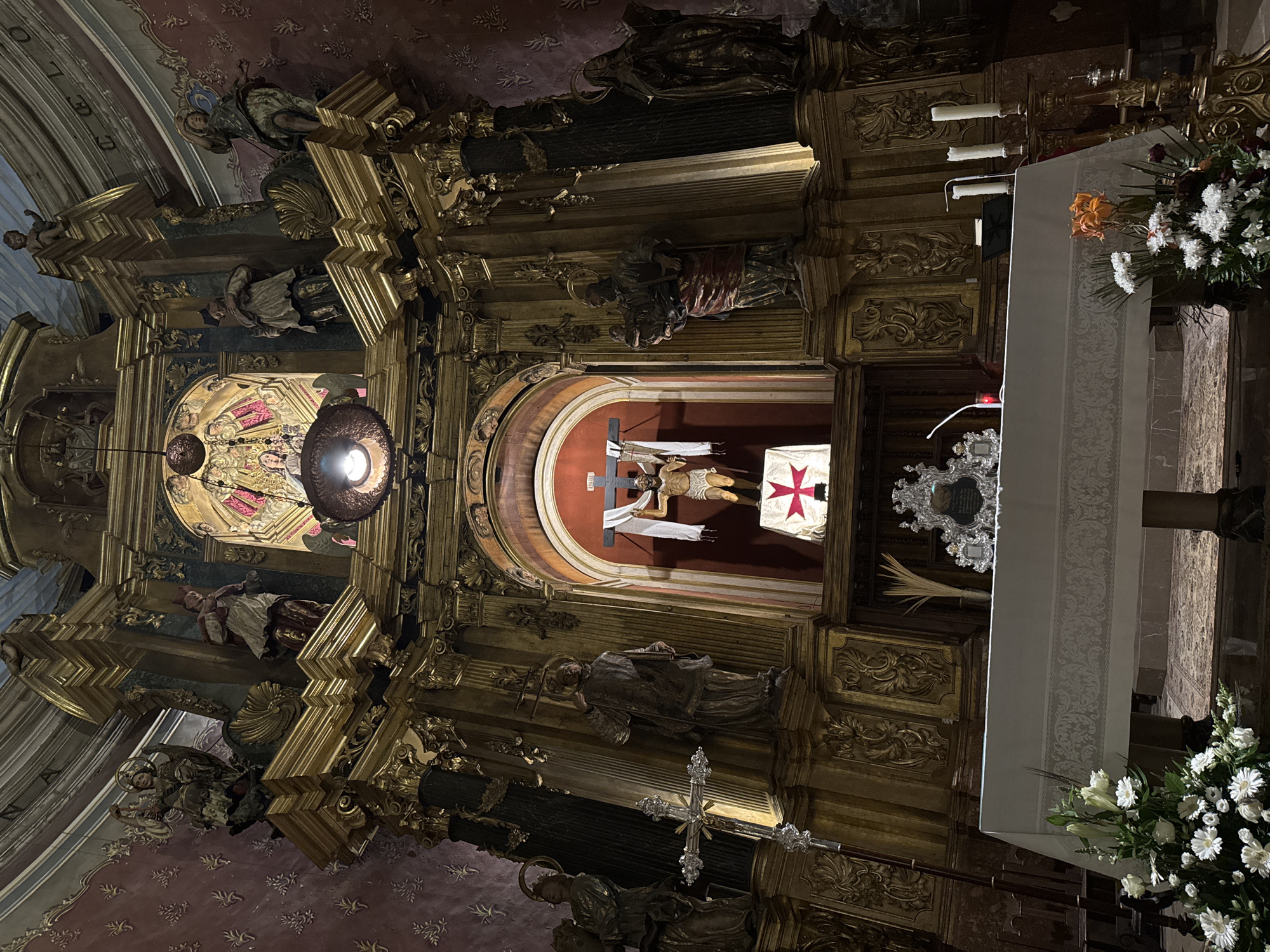 Tourist documents historic church architecture and wet streets in Pollença