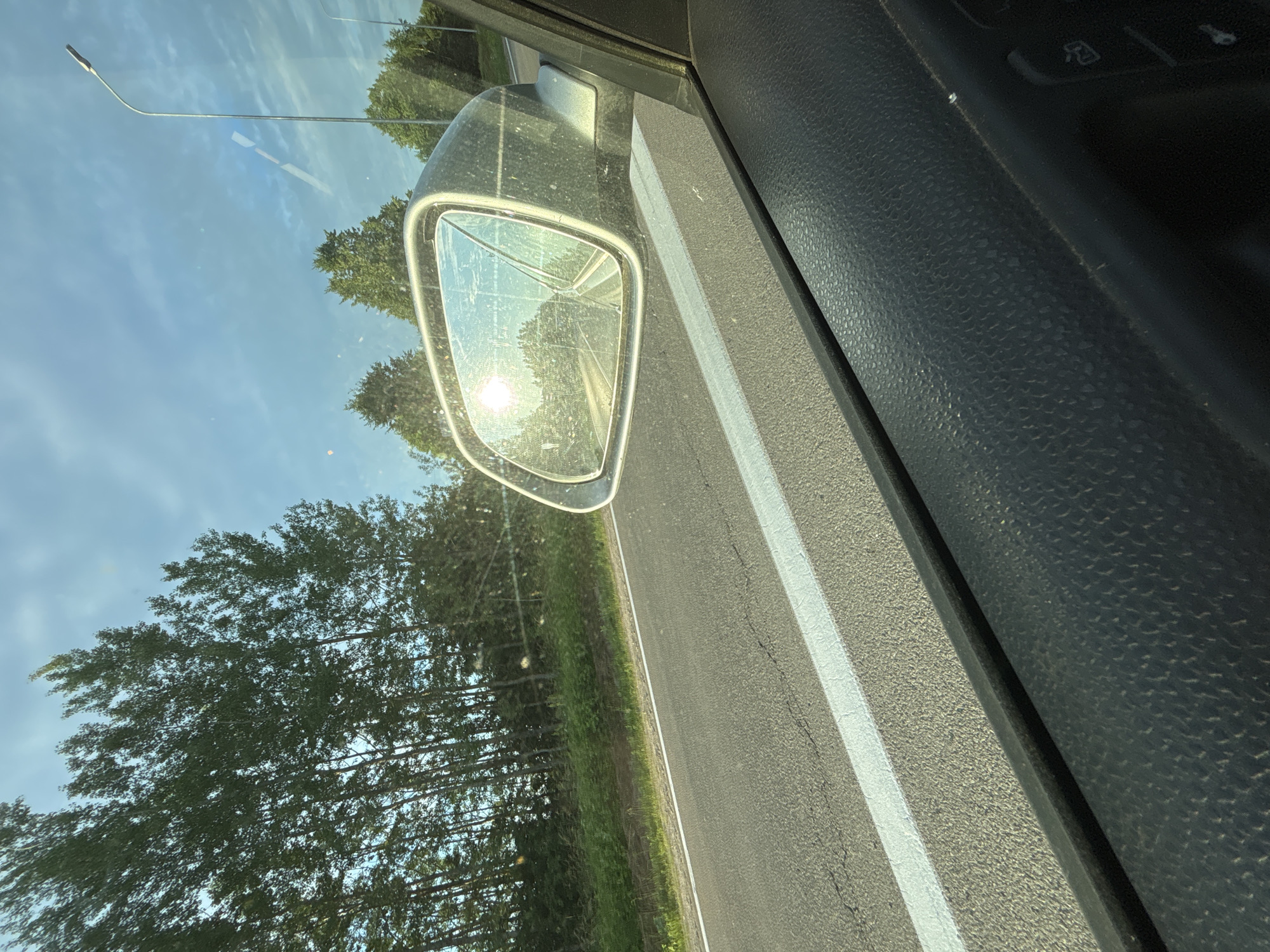 Sunset reflected in a rearview mirror on a Latvian road