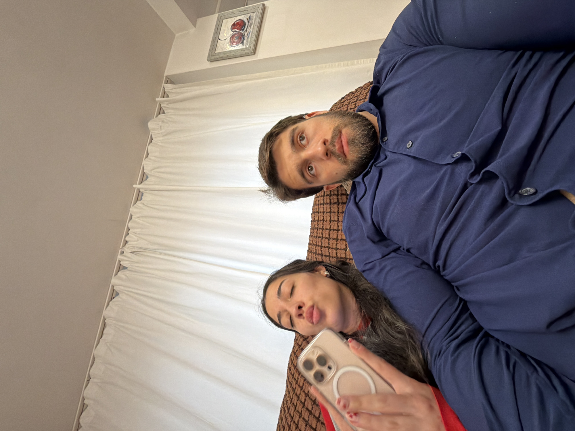 Couple relaxes on sofa, woman takes selfie in Sofia