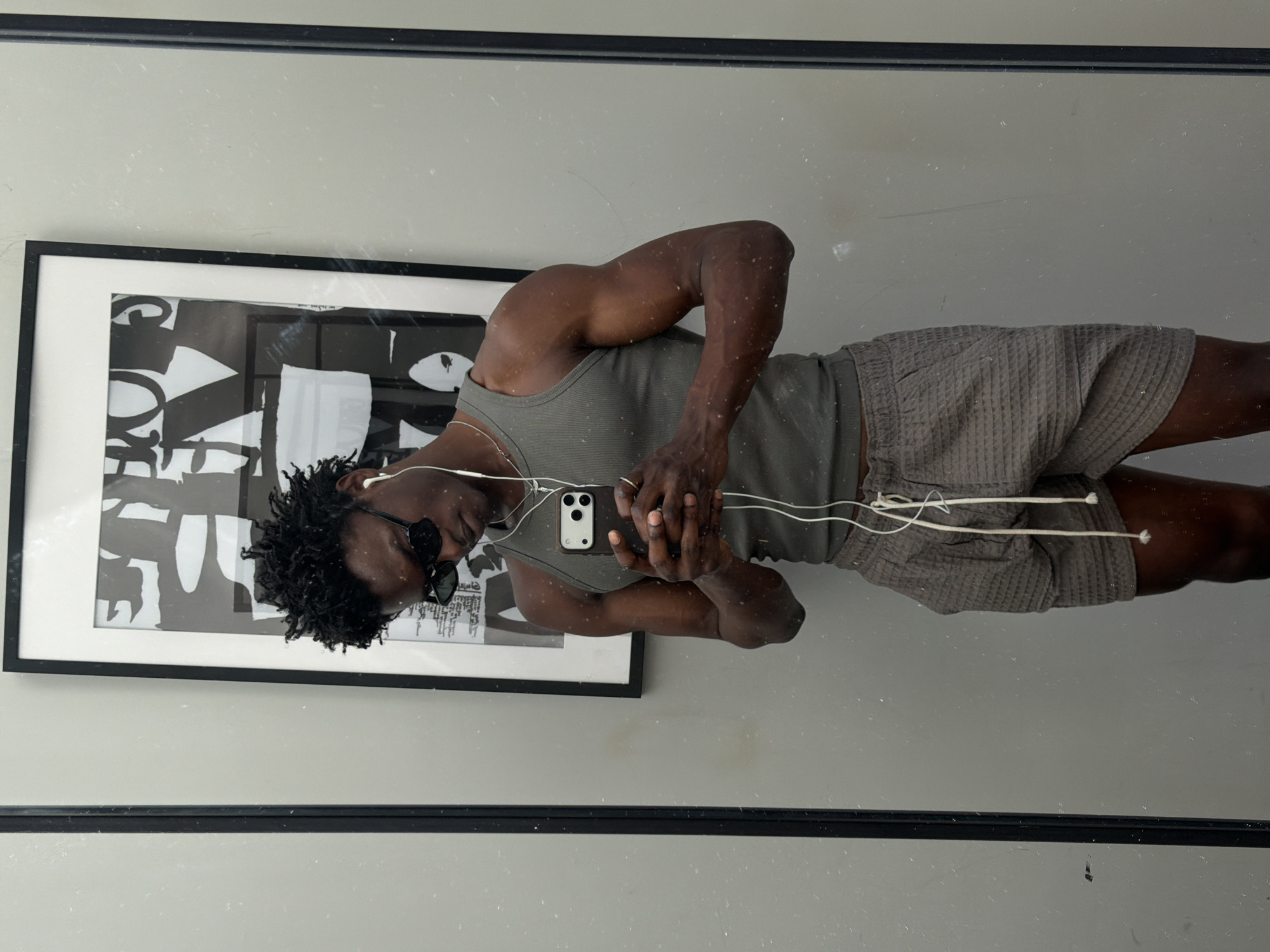 Man with smartphone and earbuds captured in London mirror reflection