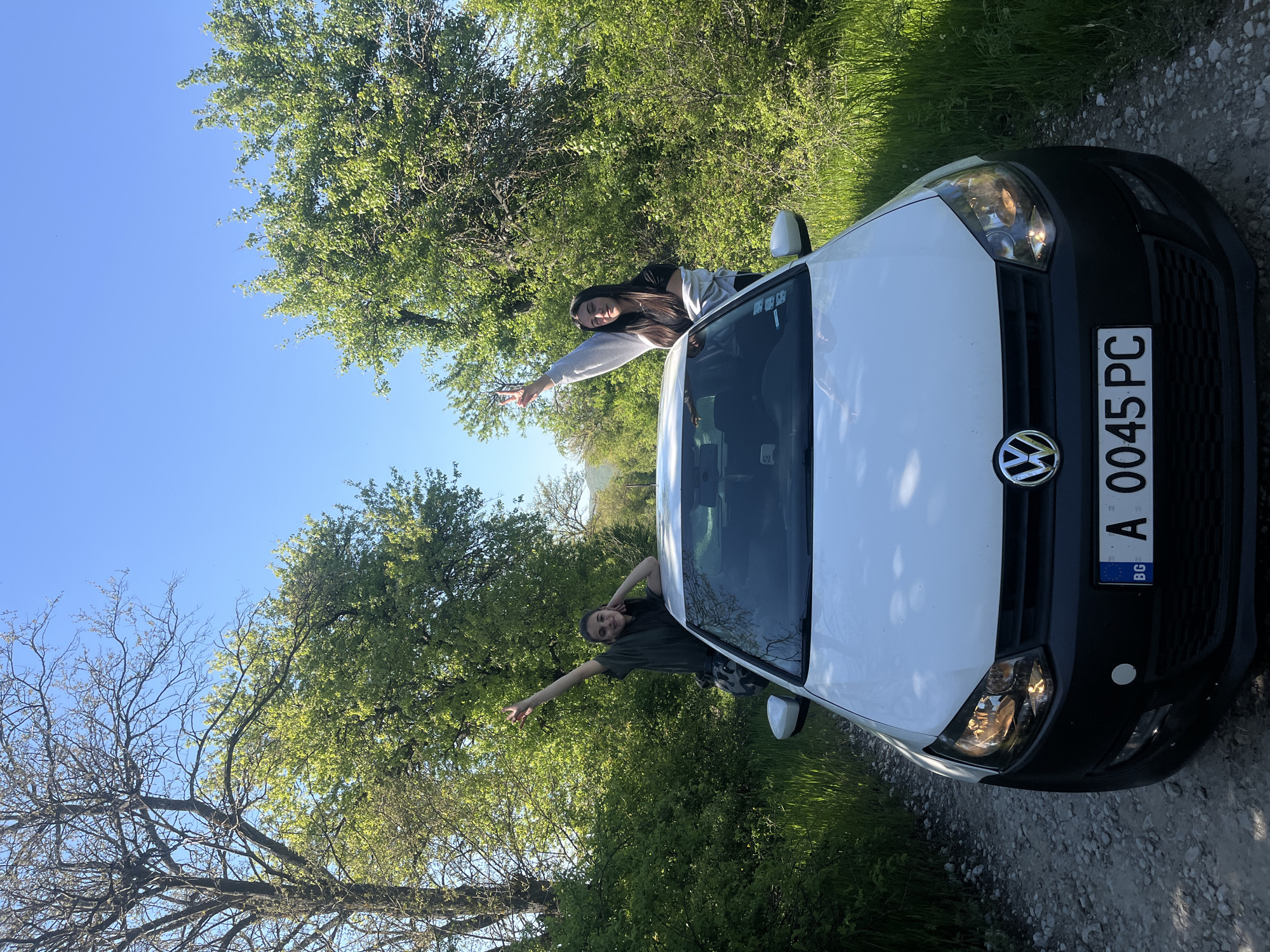 Two people pose with white Volkswagen in rural Bulgaria