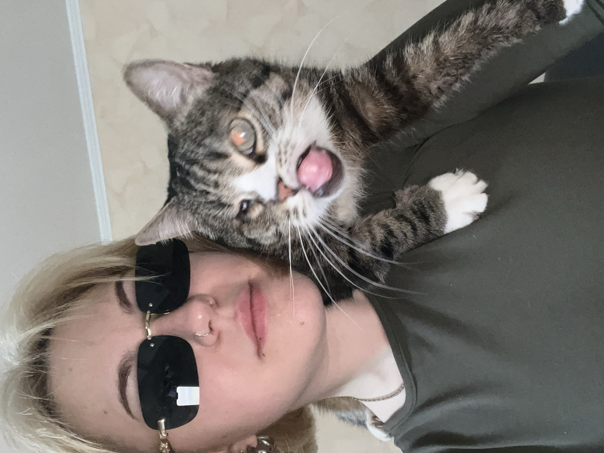 Person poses for selfie with tabby cat on shoulder