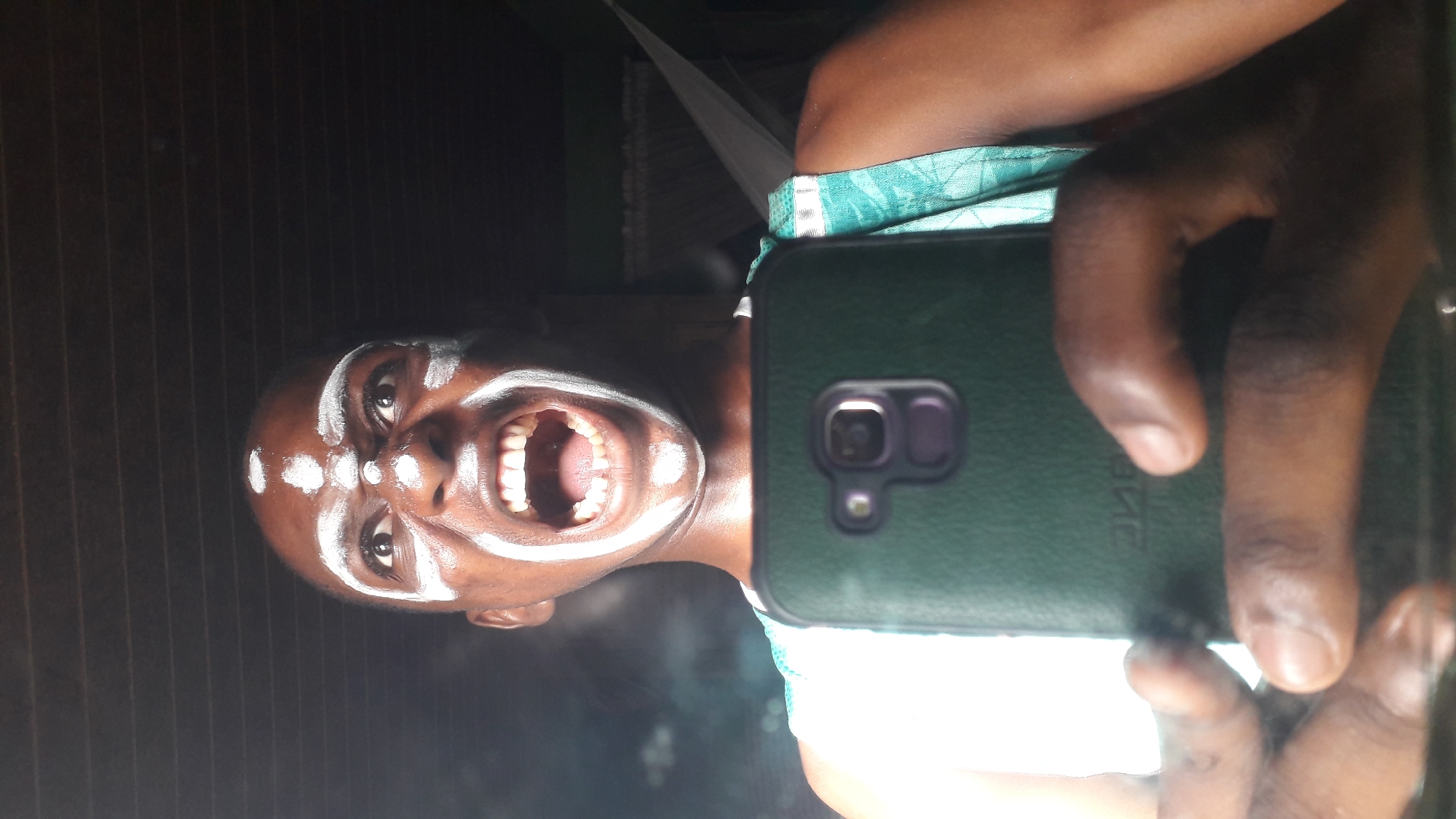 Person documents selfie session with ceremonial face paint in Nigeria