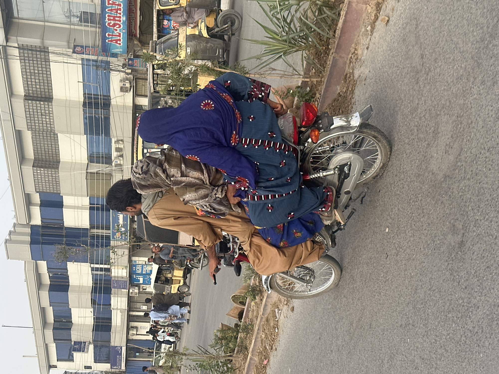 Busy street life in Quetta: motorcycles, pedestrians, and decorated rickshaws