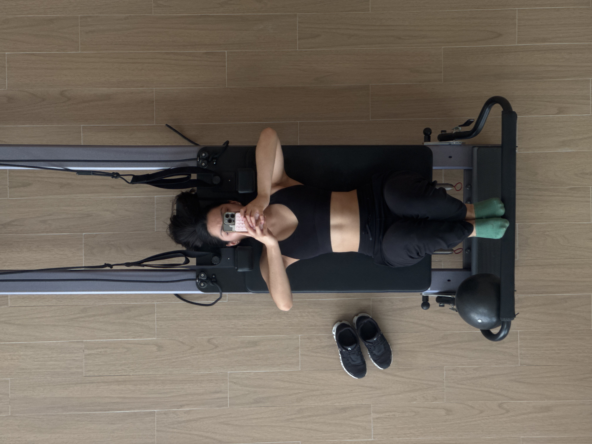 Woman multitasks with phone during home Pilates workout session