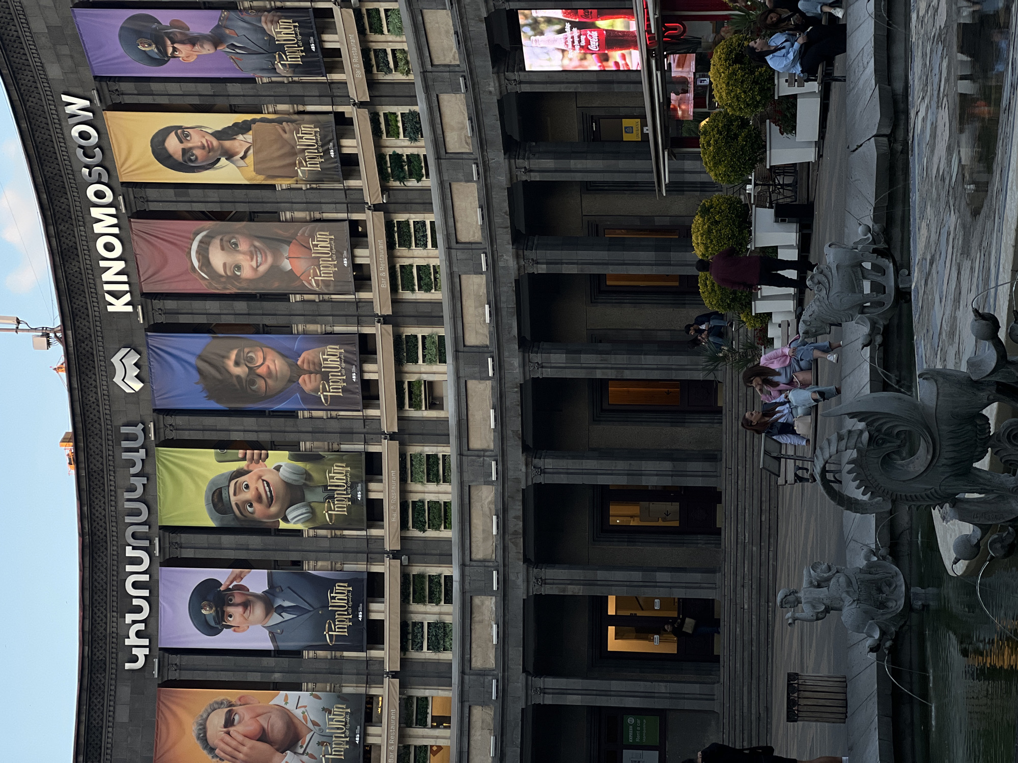 Urban scenes documented near KINOMOSCOW building with sculptures and cafés