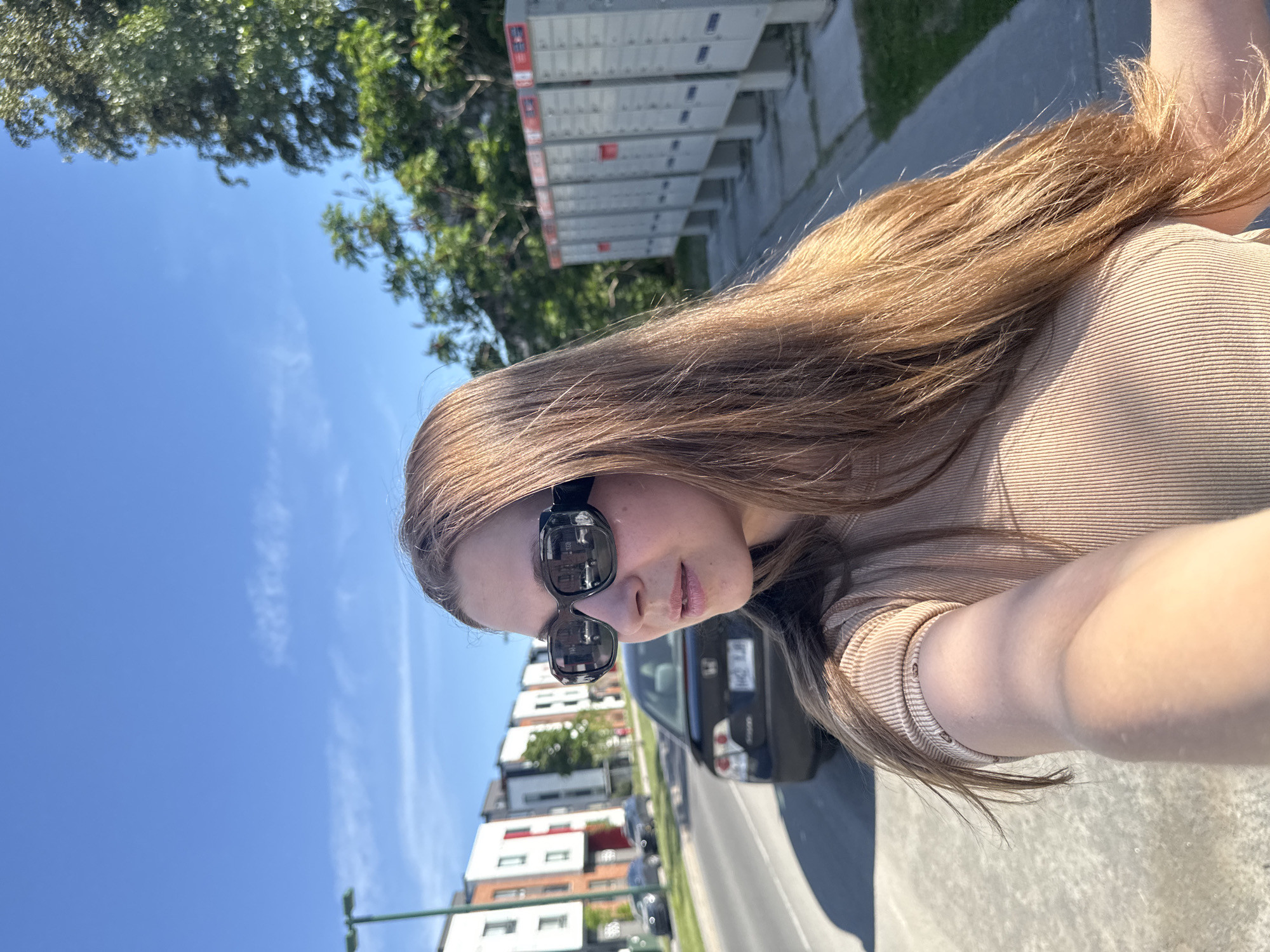 Person takes sunny afternoon selfies in Gatineau street scene