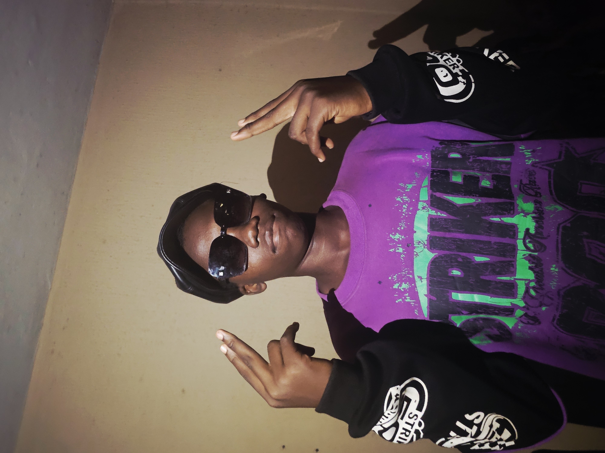 Young man in graphic shirt photographed indoors in Nkwelle