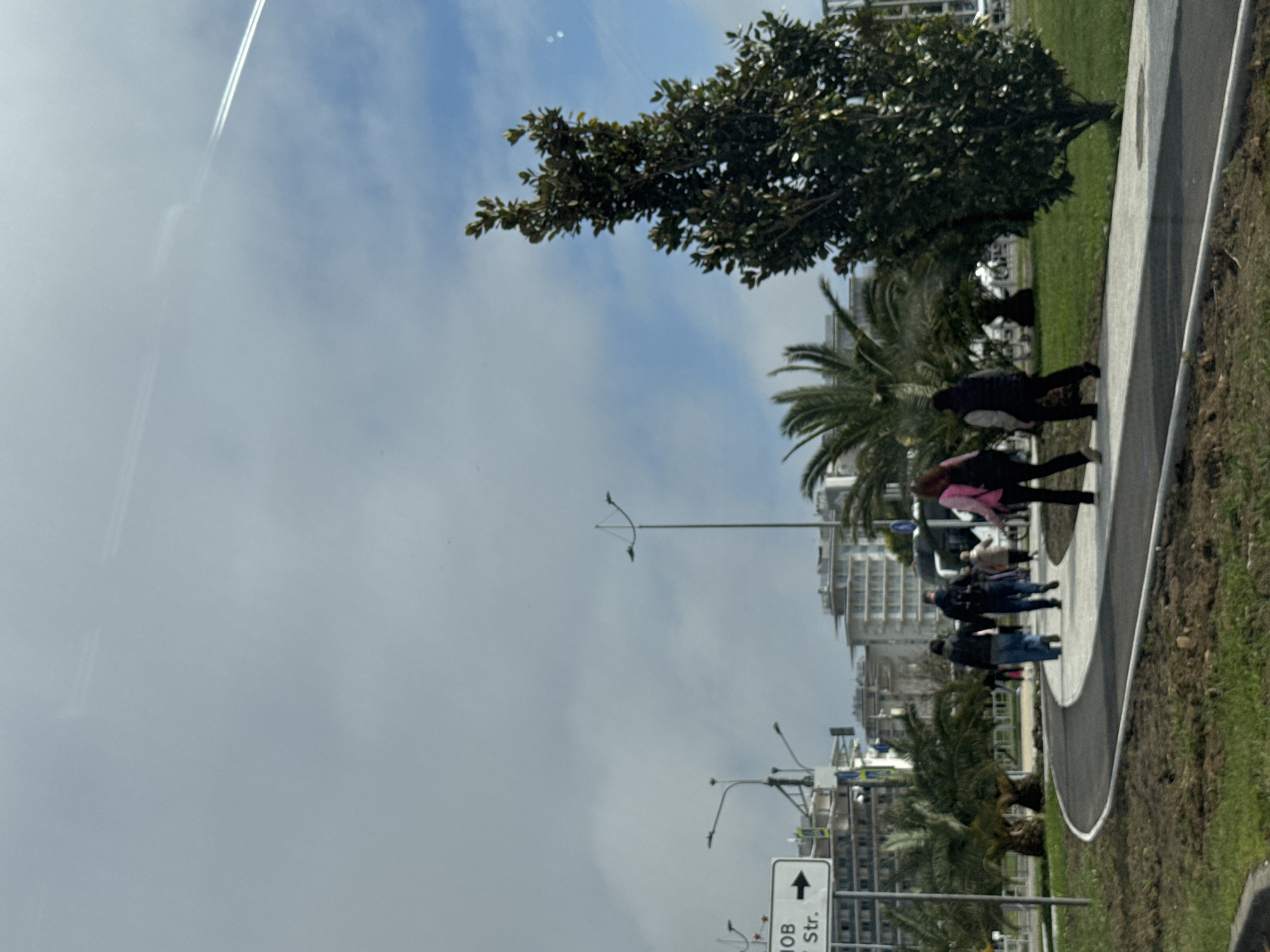 Pedestrians walk sidewalk in Sirius, Russia under cloudy skies