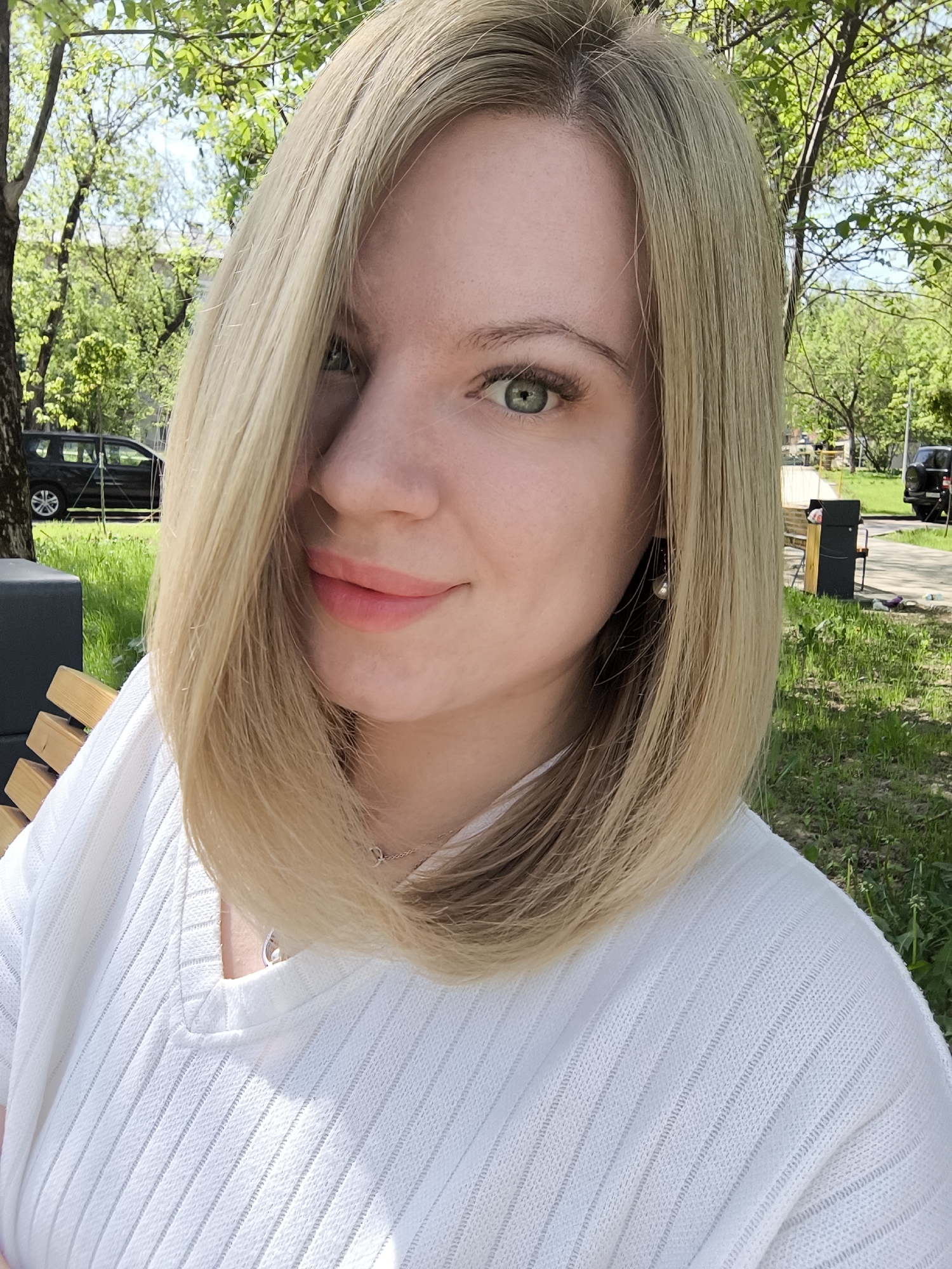 Woman sits on bench, person reads Russian book in Fryazino park