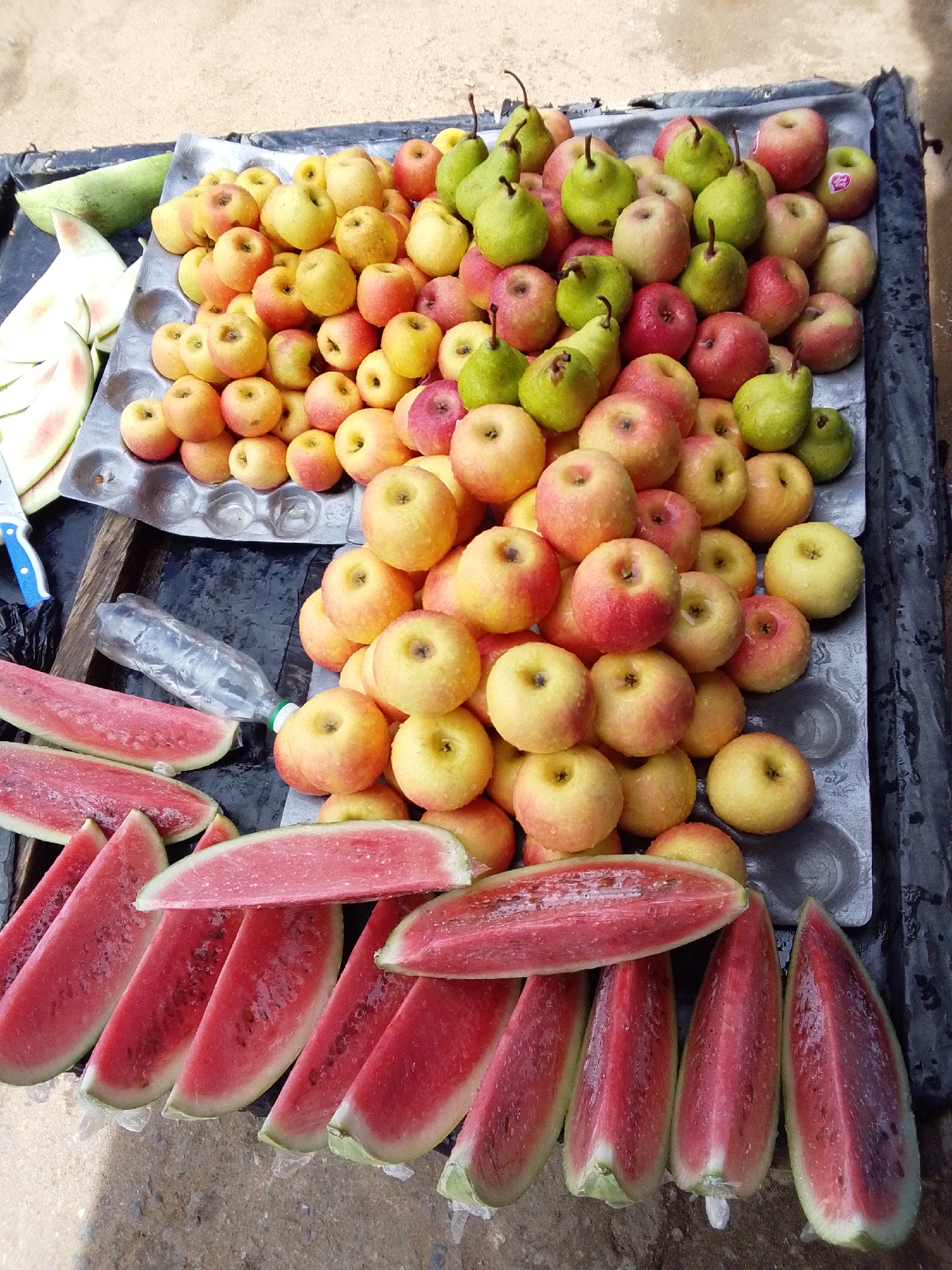 Fresh fruit stall in Serti, Nigeria, watermelon and wet apples on display
