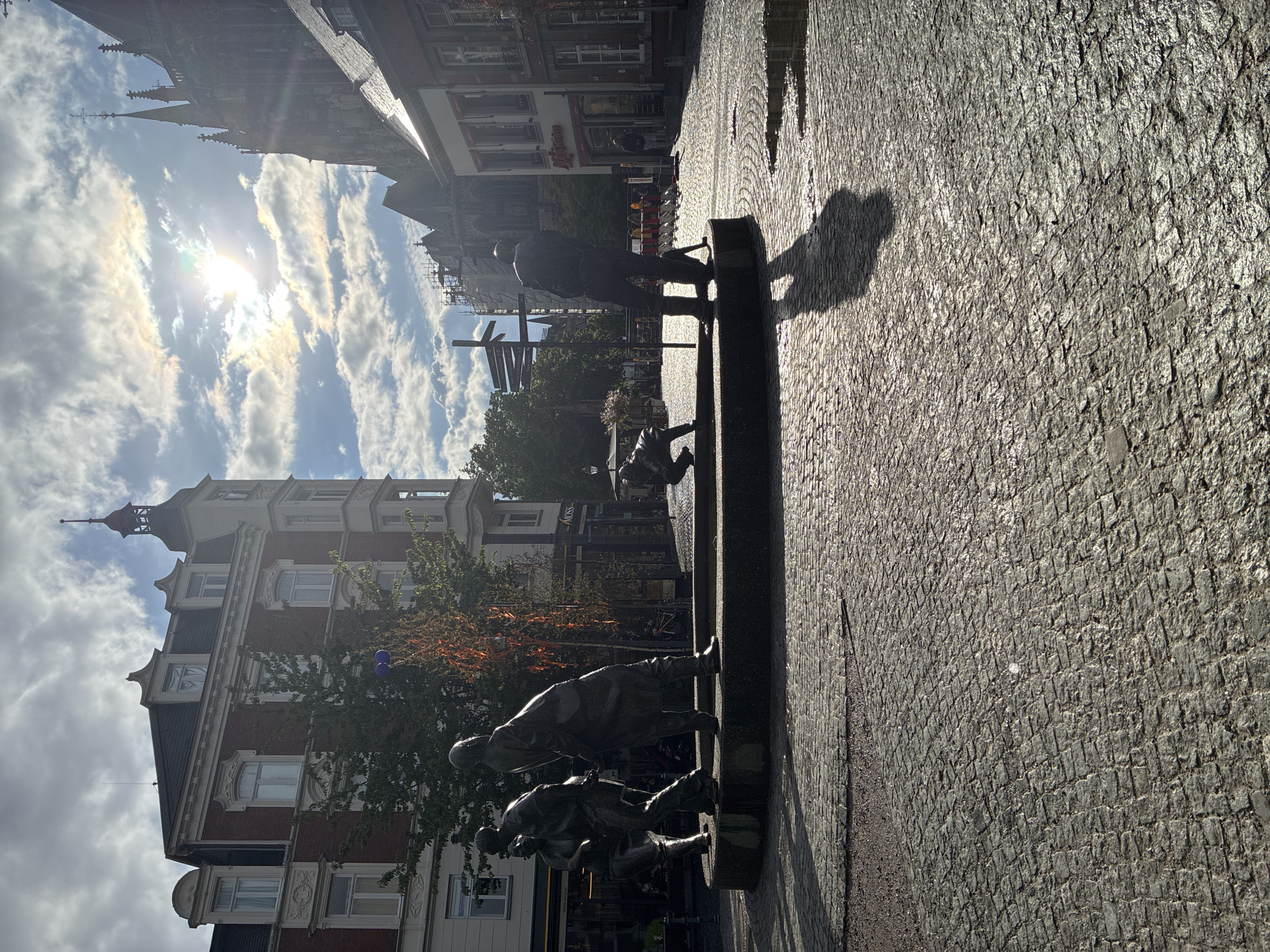 Visitors document sunny afternoon at Aachen's historic Bahkauv fountain