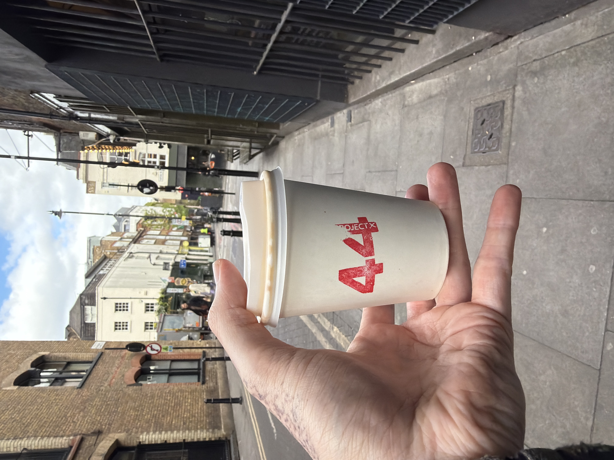 Coffee cup held on London street amid mixed architecture