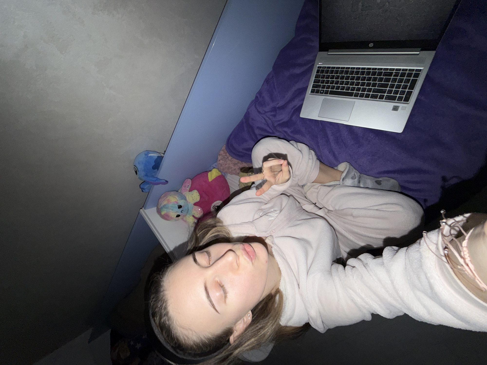 Woman relaxes with laptop and stuffed animals in Plovdiv bedroom