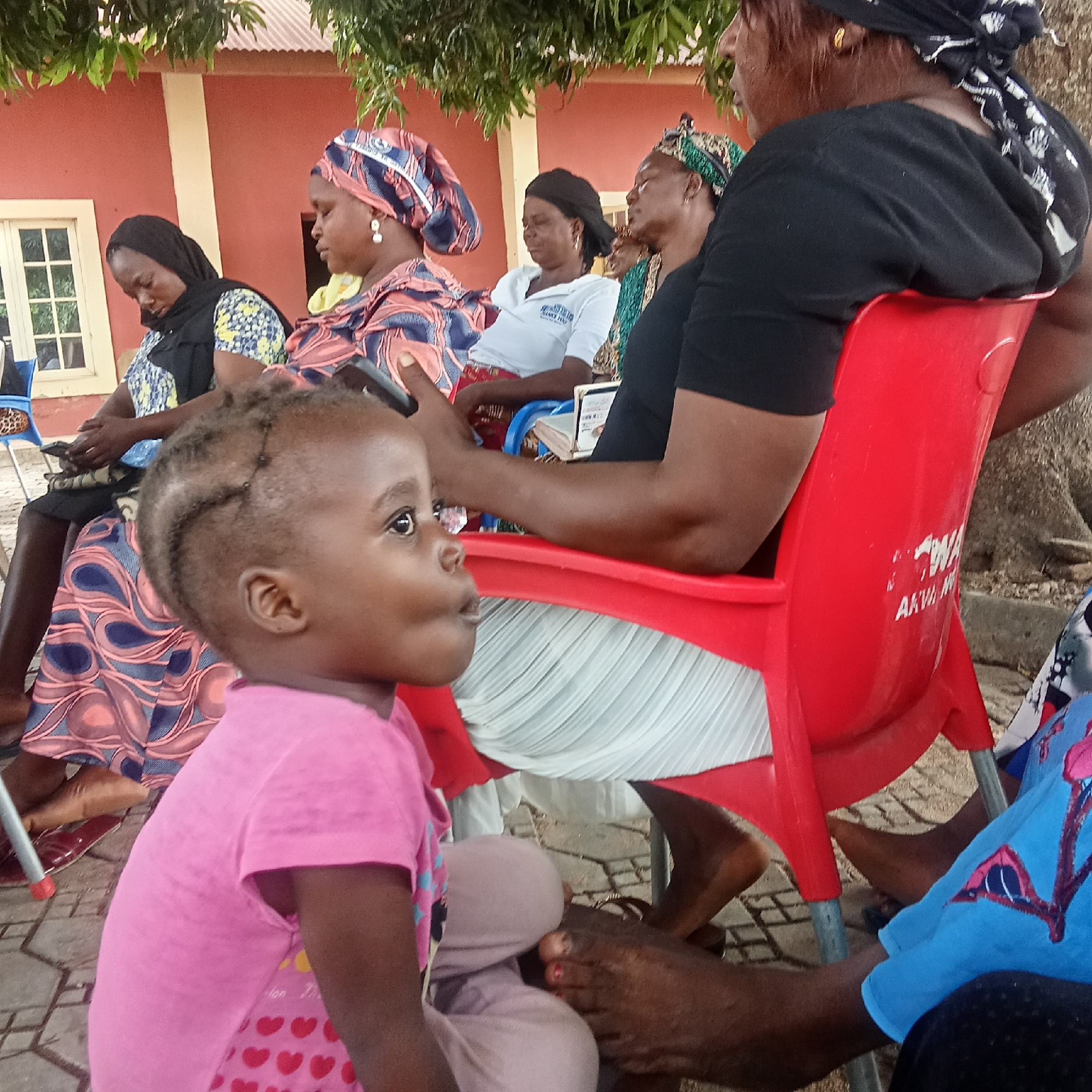 Women gather on plastic chairs with child in Akwanga