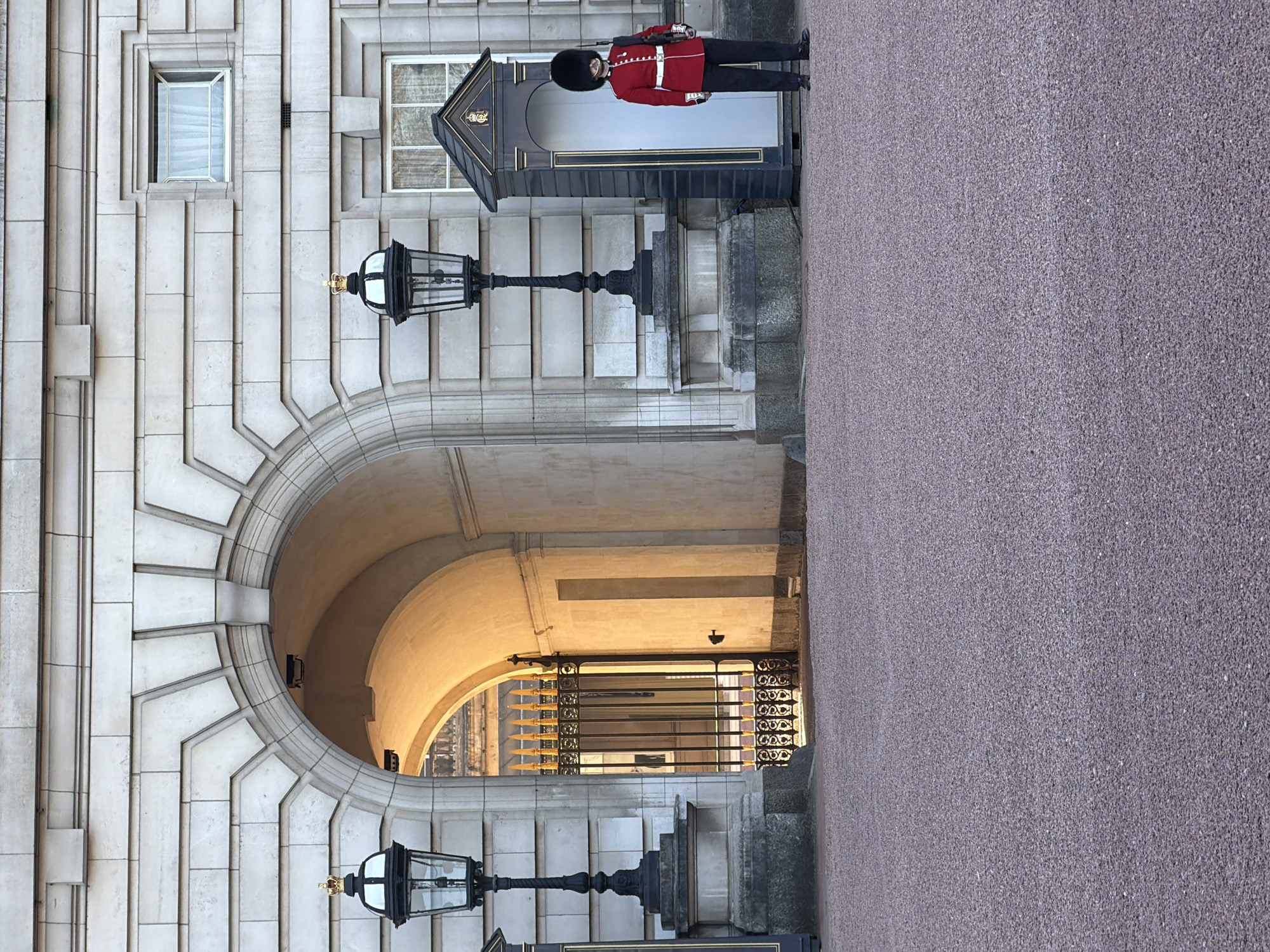 Traditional British guard stands watch at London stone archway