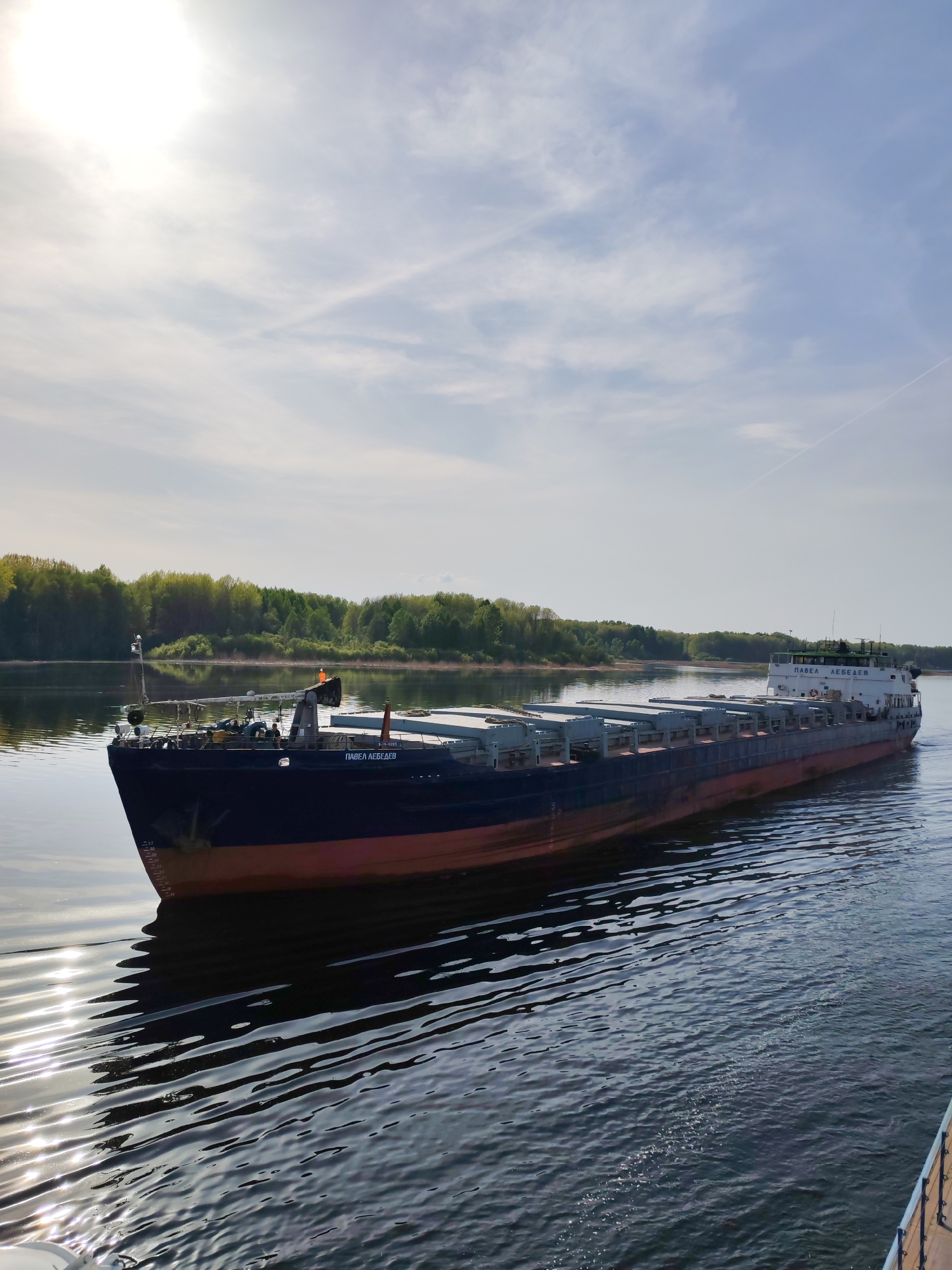 Cargo barge navigates Russian river carrying containerized freight