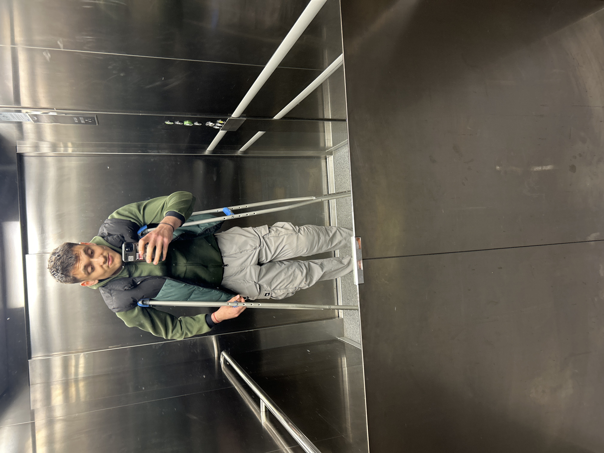 Man with crutches uses phone in Varna elevator