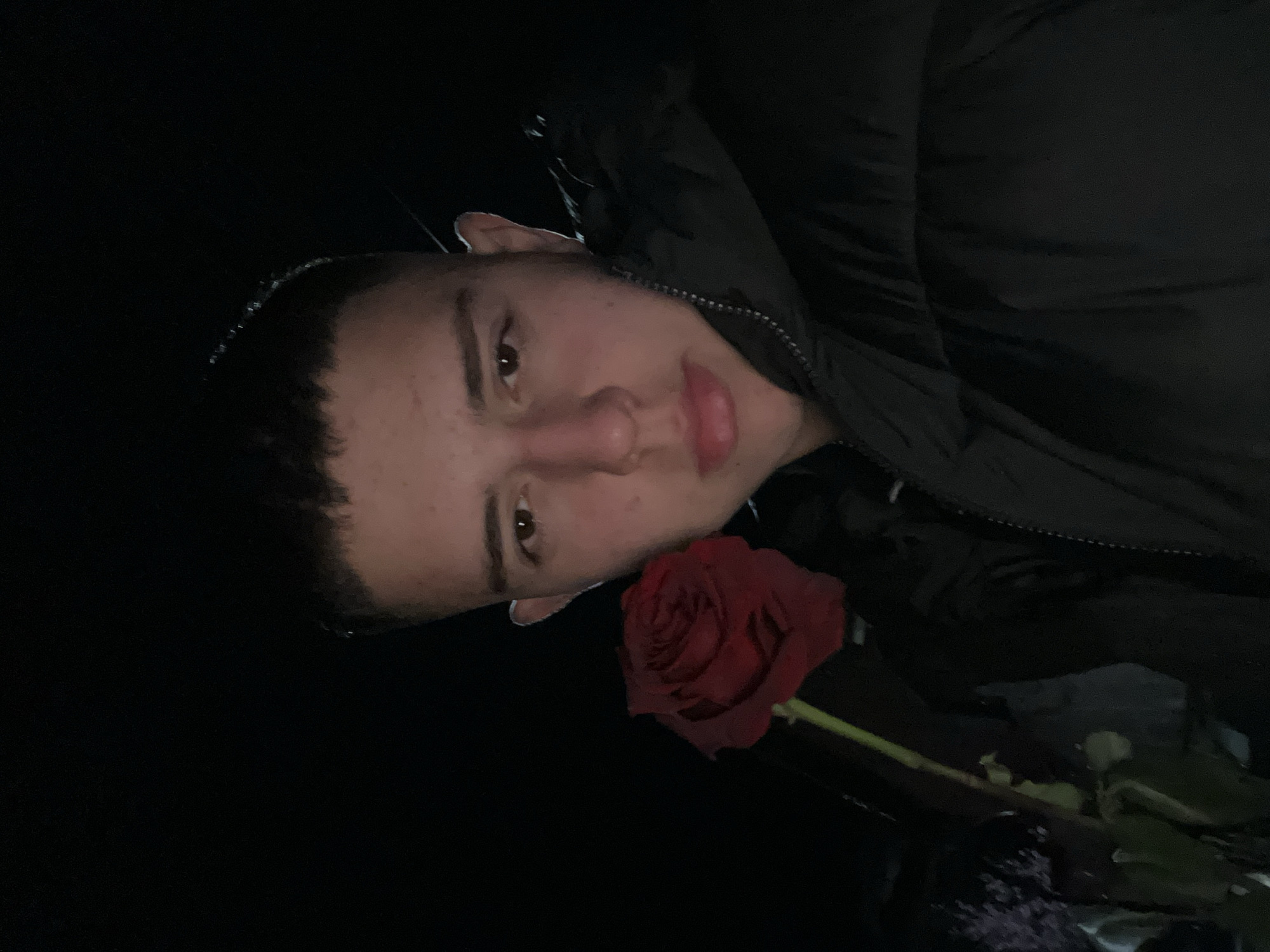 Person with red rose observed on wet street in Zlatograd