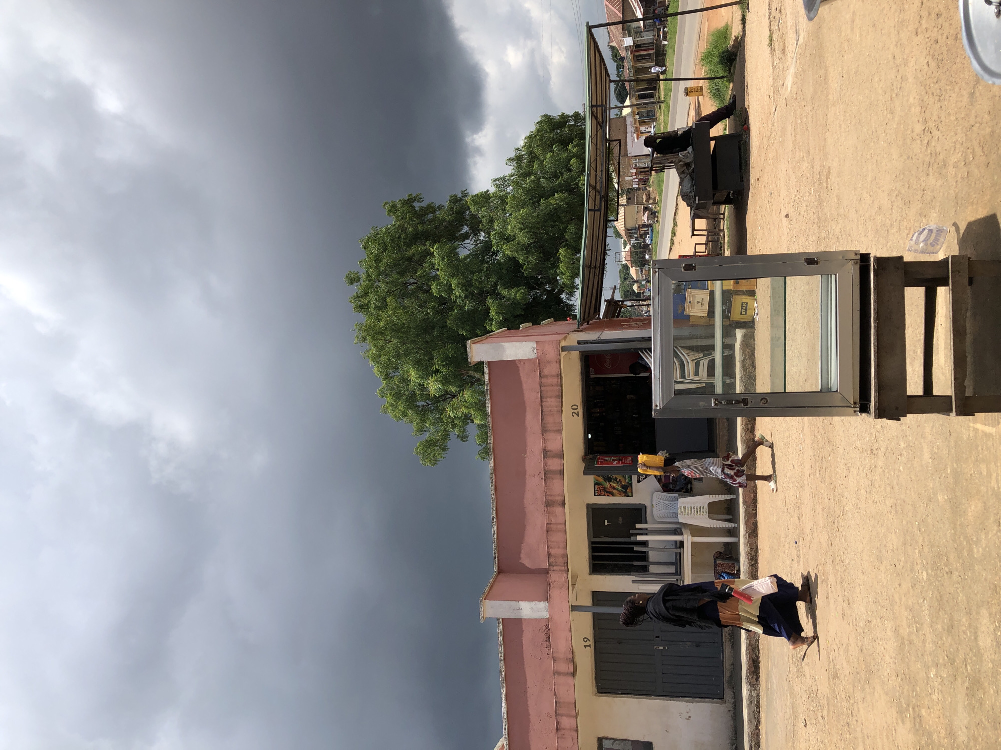 Market day and street life in Jos, Nigeria, under storm clouds