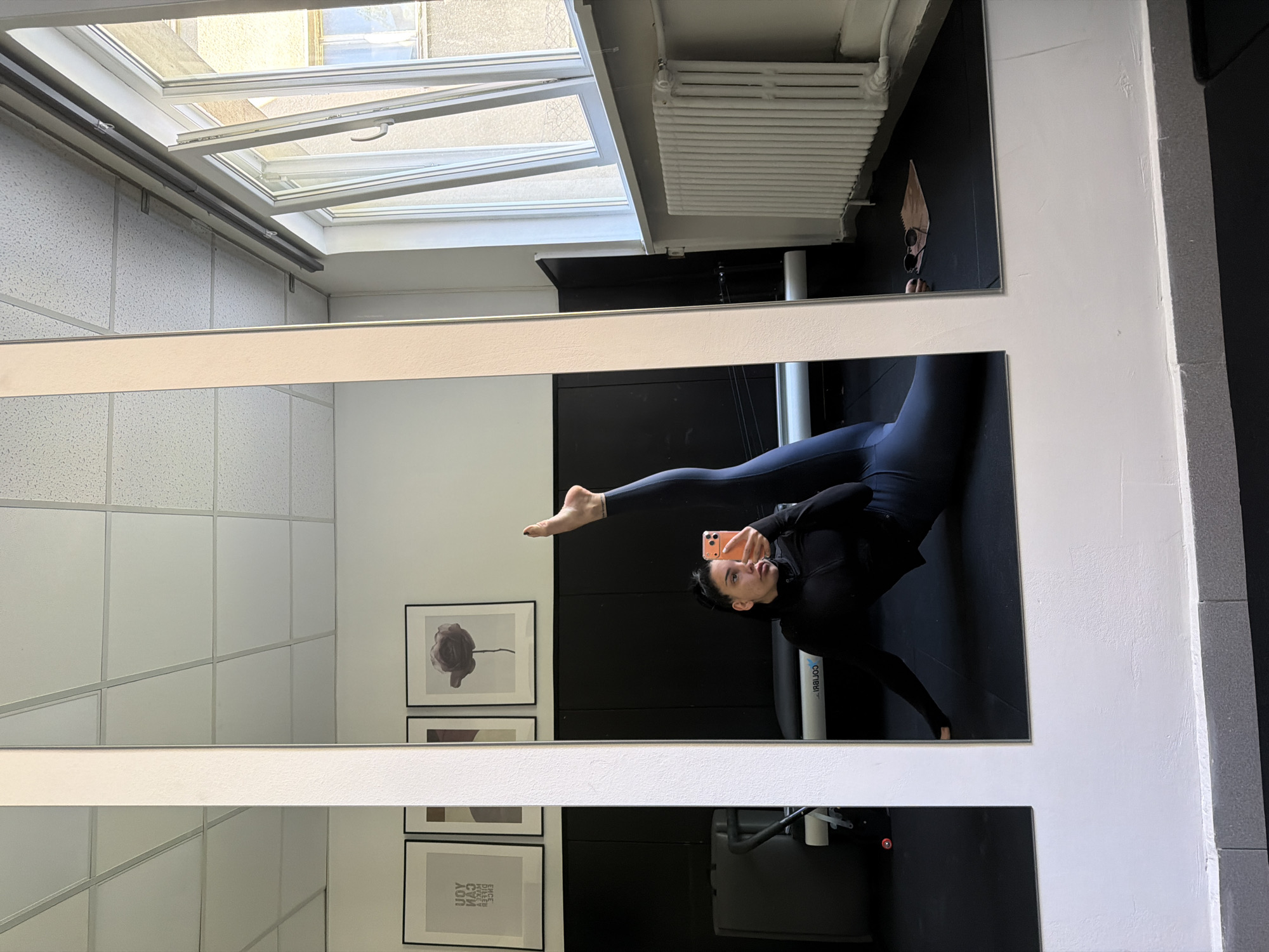 Woman performs yoga pose in fitness studio mirror selfie