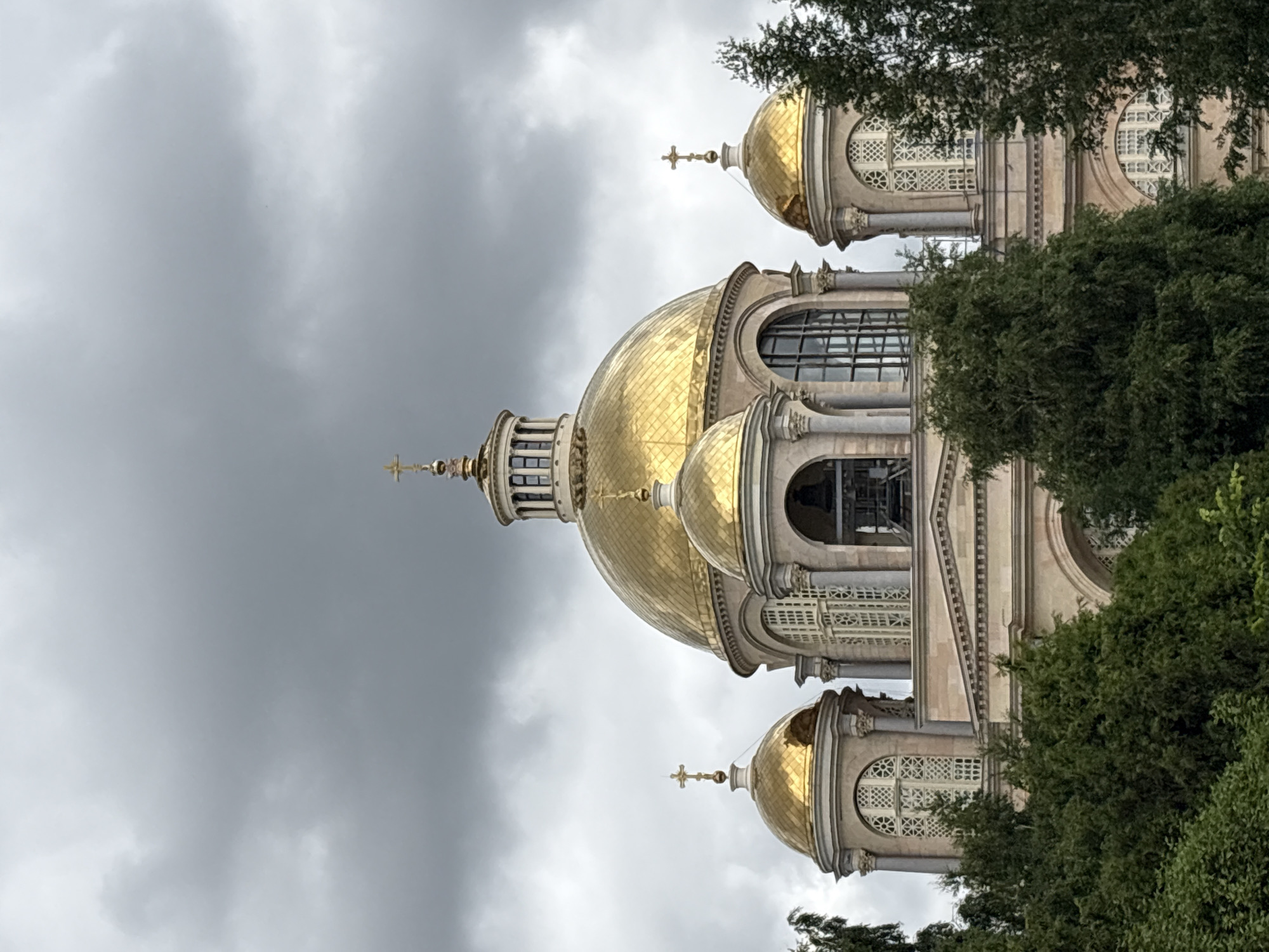 Golden domes of a Saint Petersburg Orthodox cathedral under grey skies