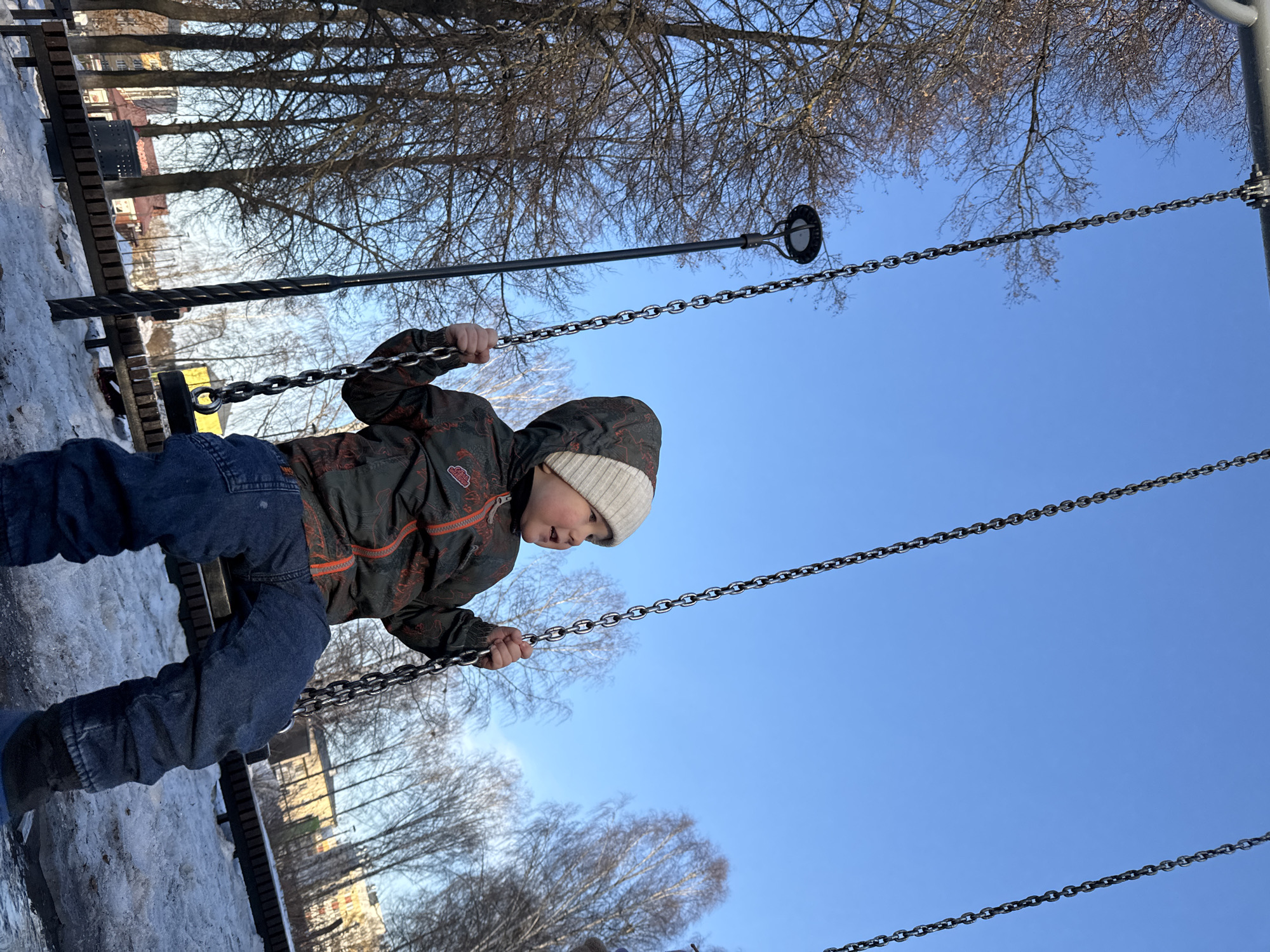 Child plays on swing in snowy playground in Russia