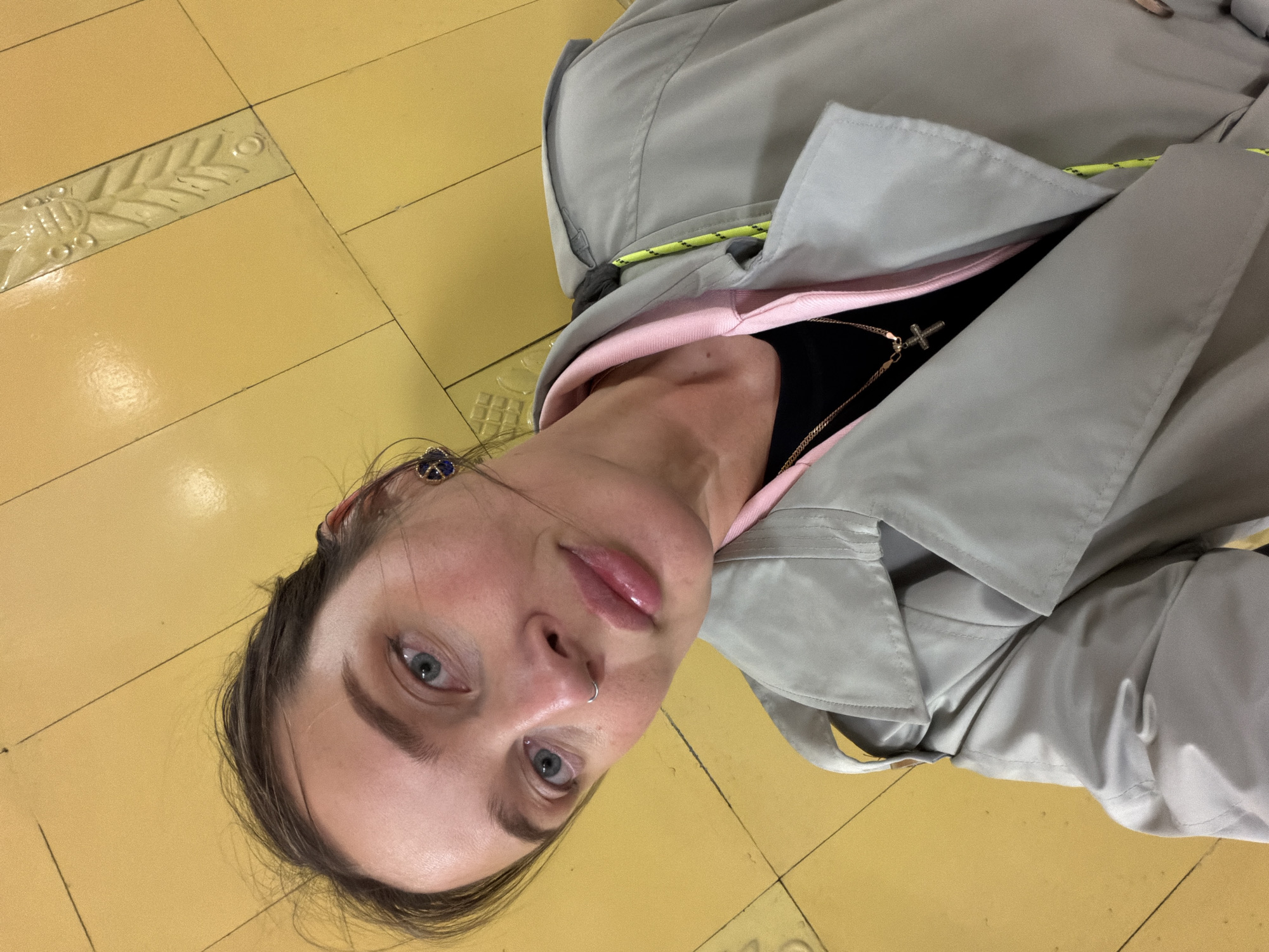 Woman in gray coat observed on Moscow tiled floor