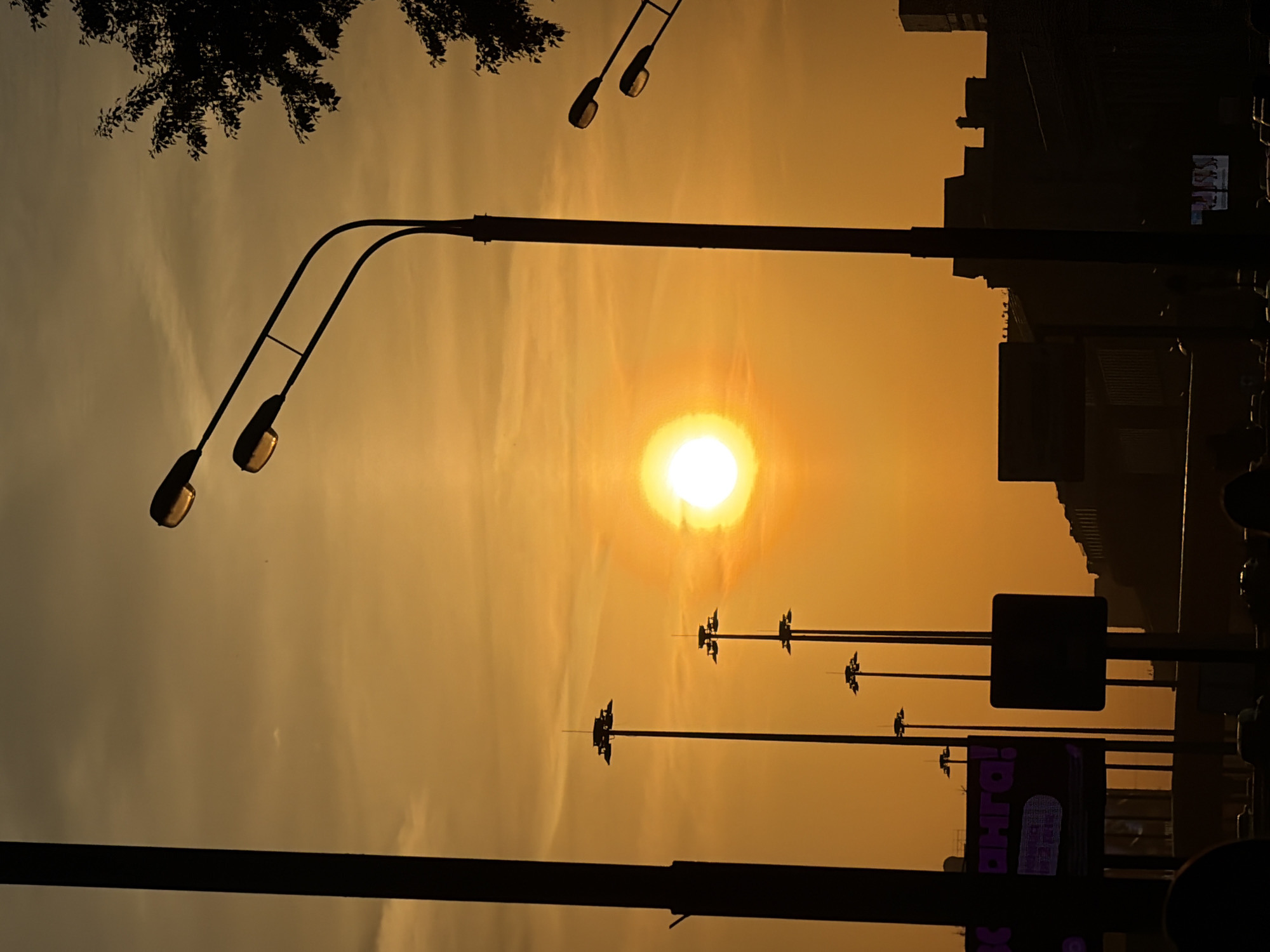 Urban sunset documented with silhouetted streetlights visible