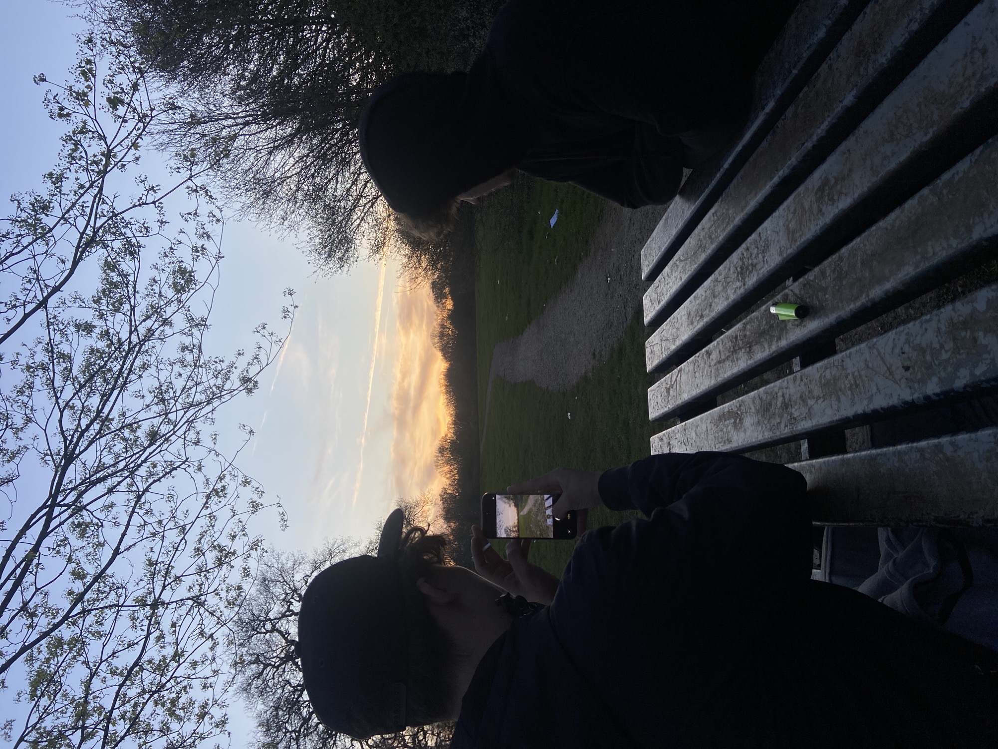 Park visitors photograph sunset from bench in Broxbourne