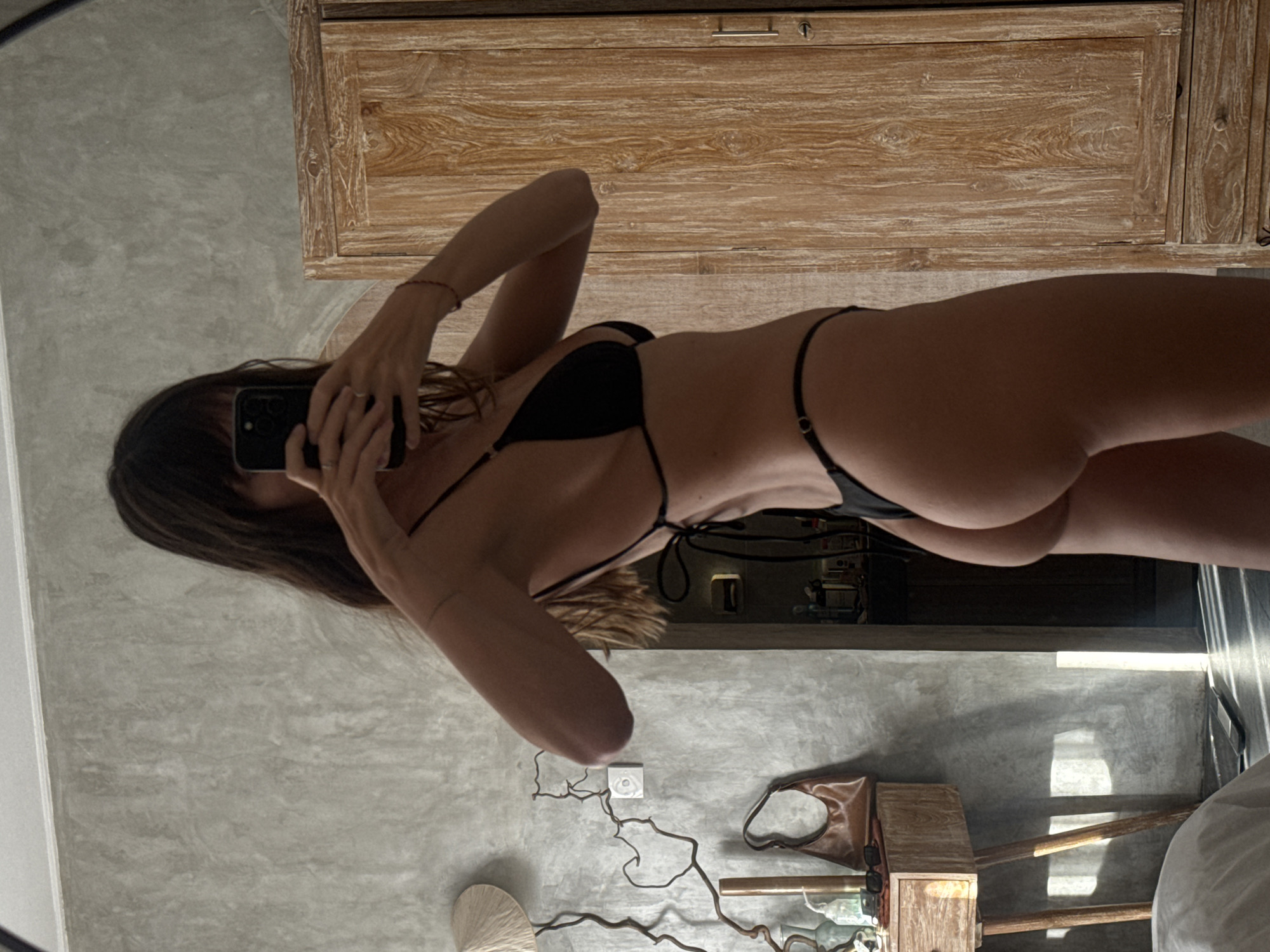 Woman takes mirror selfie in black bikini, North Kuta