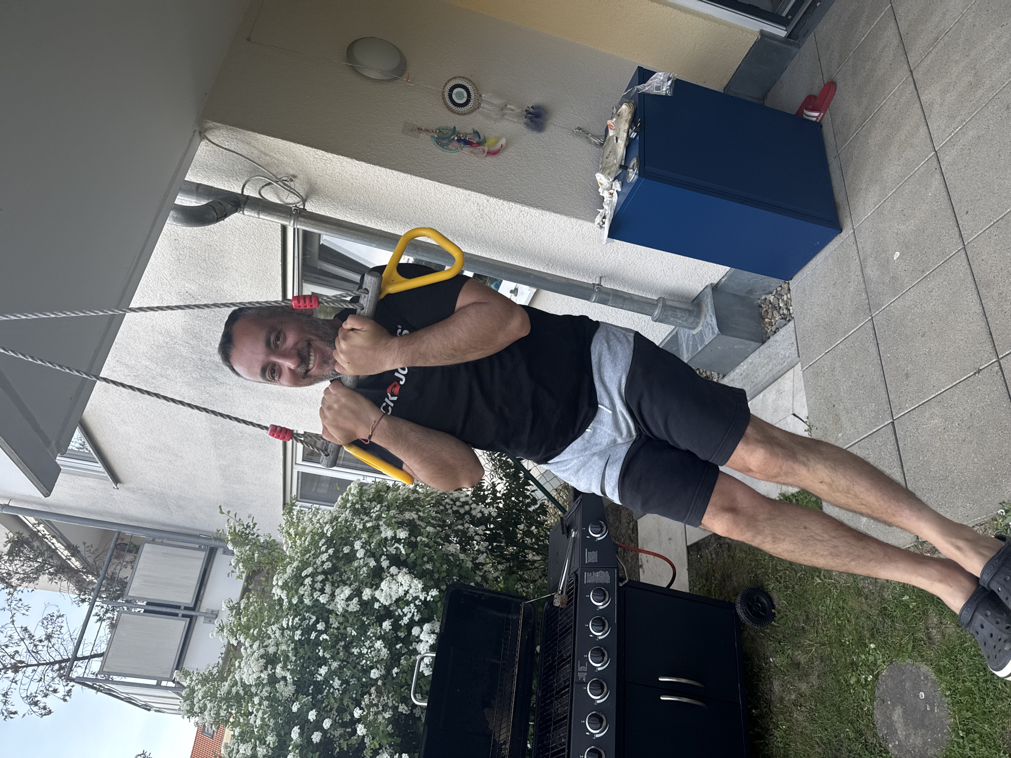 Man exercises with trapeze, soccer juggling in German backyard