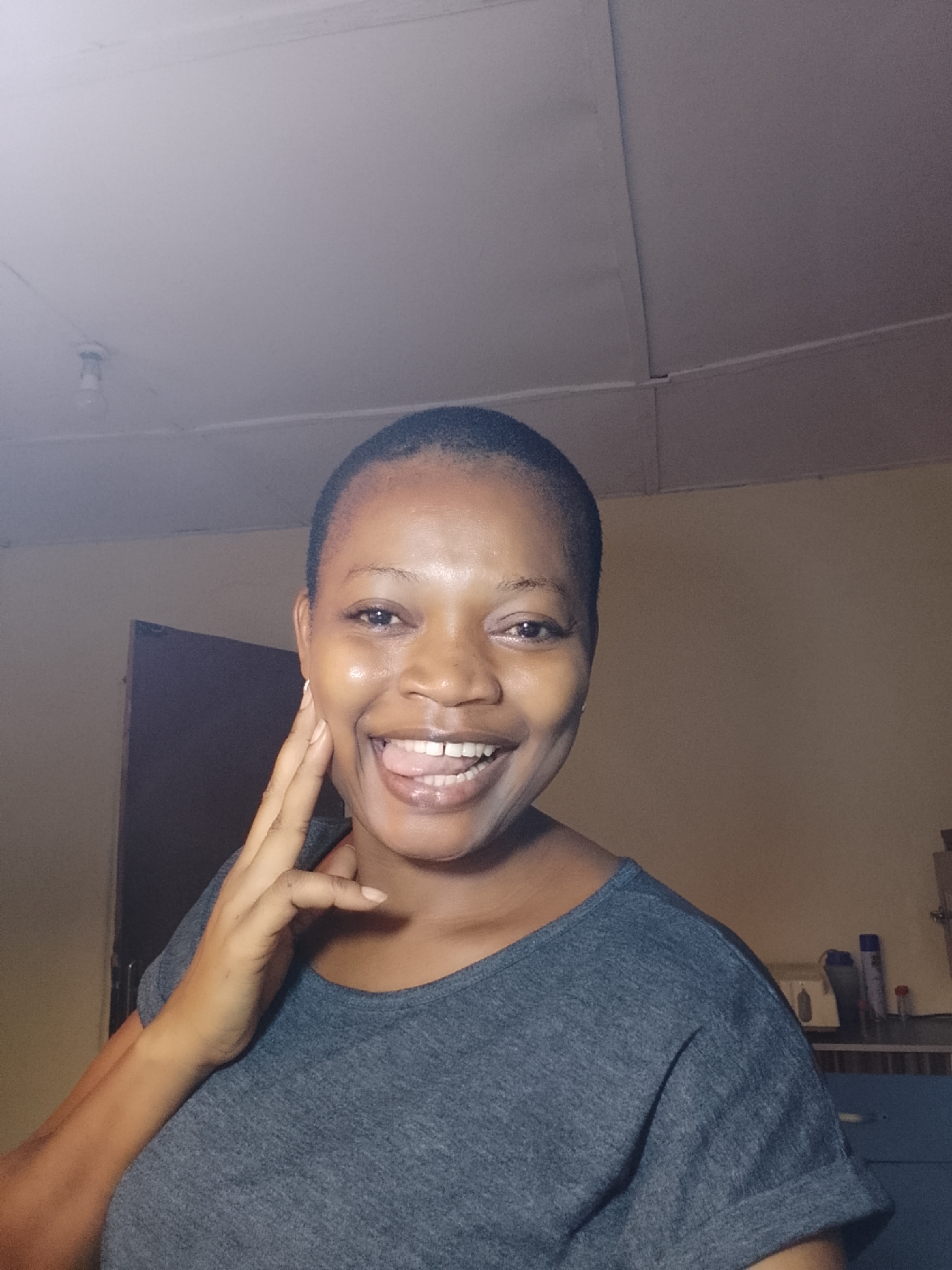 Woman makes playful gestures indoors in Agani, Nigeria