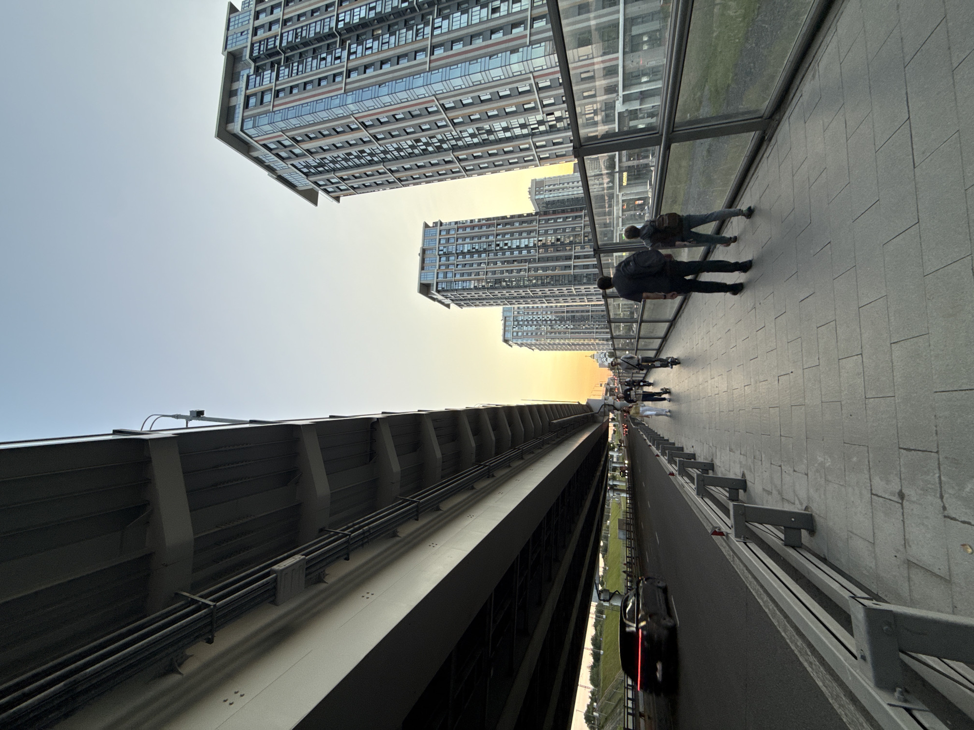 Dusk along a Moscow sidewalk beneath an elevated highway