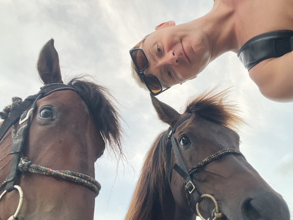 Tourist documents beach day with horses in Jimbaran, Indonesia