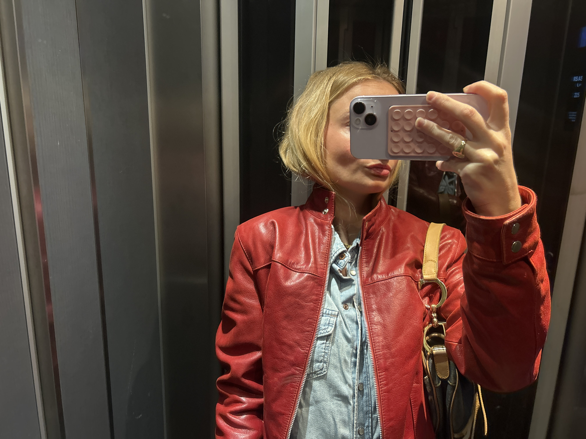 Woman Takes Selfie in Elevator While Wearing Red Jacket