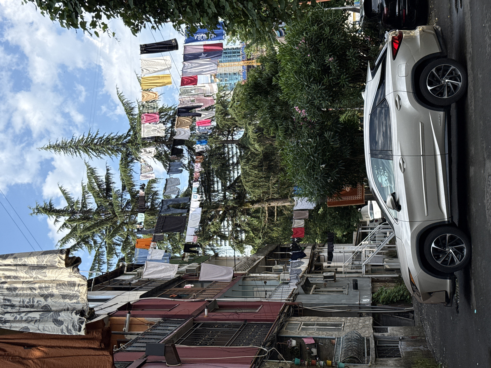 Street-level urban scene: parked vehicles, hotels, and weathered apartment blocks