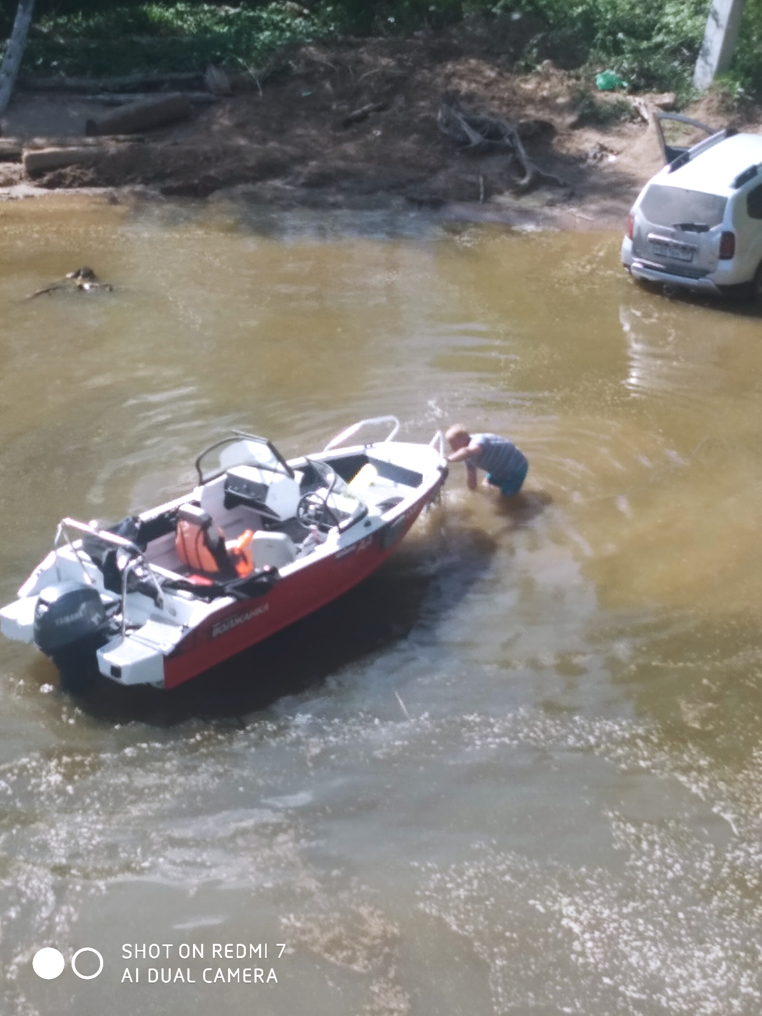 Vehicle partially submerged in Chaikovsky waters, boat and helicopter present