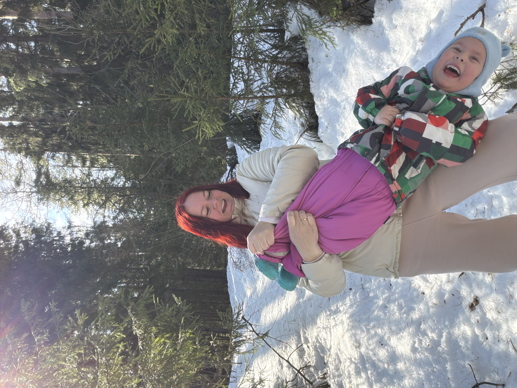 Mother and child play in spring snow melt in Chaikovsky